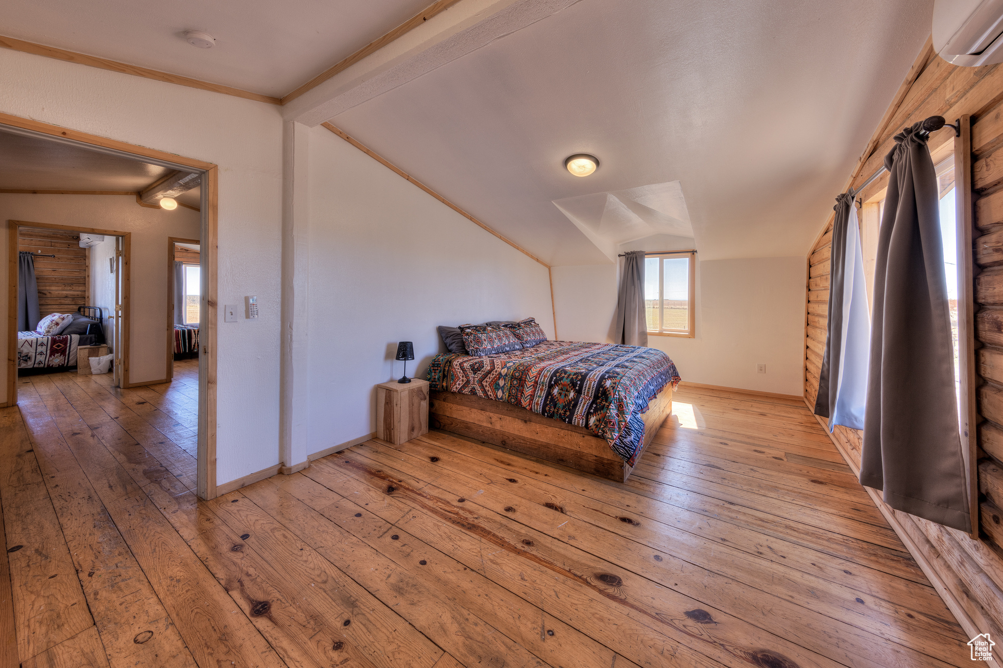 Bedroom featuring light wood-type flooring, a wall mounted AC, and vaulted ceiling