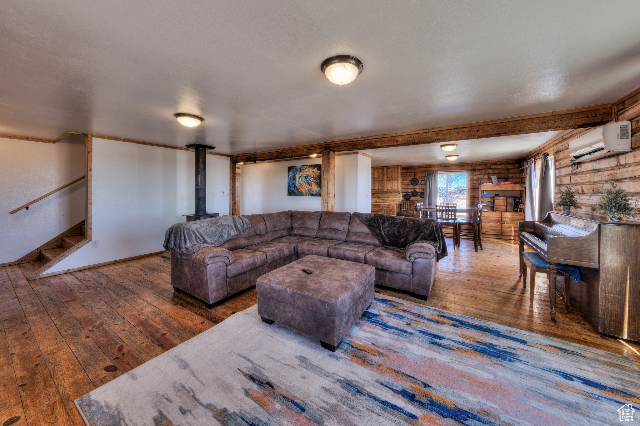 Living room featuring hardwood / wood-style flooring, a wood stove, and a wall mounted AC