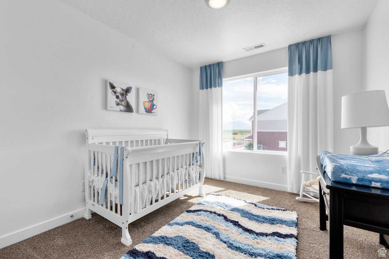 Carpeted bedroom with a textured ceiling and a crib