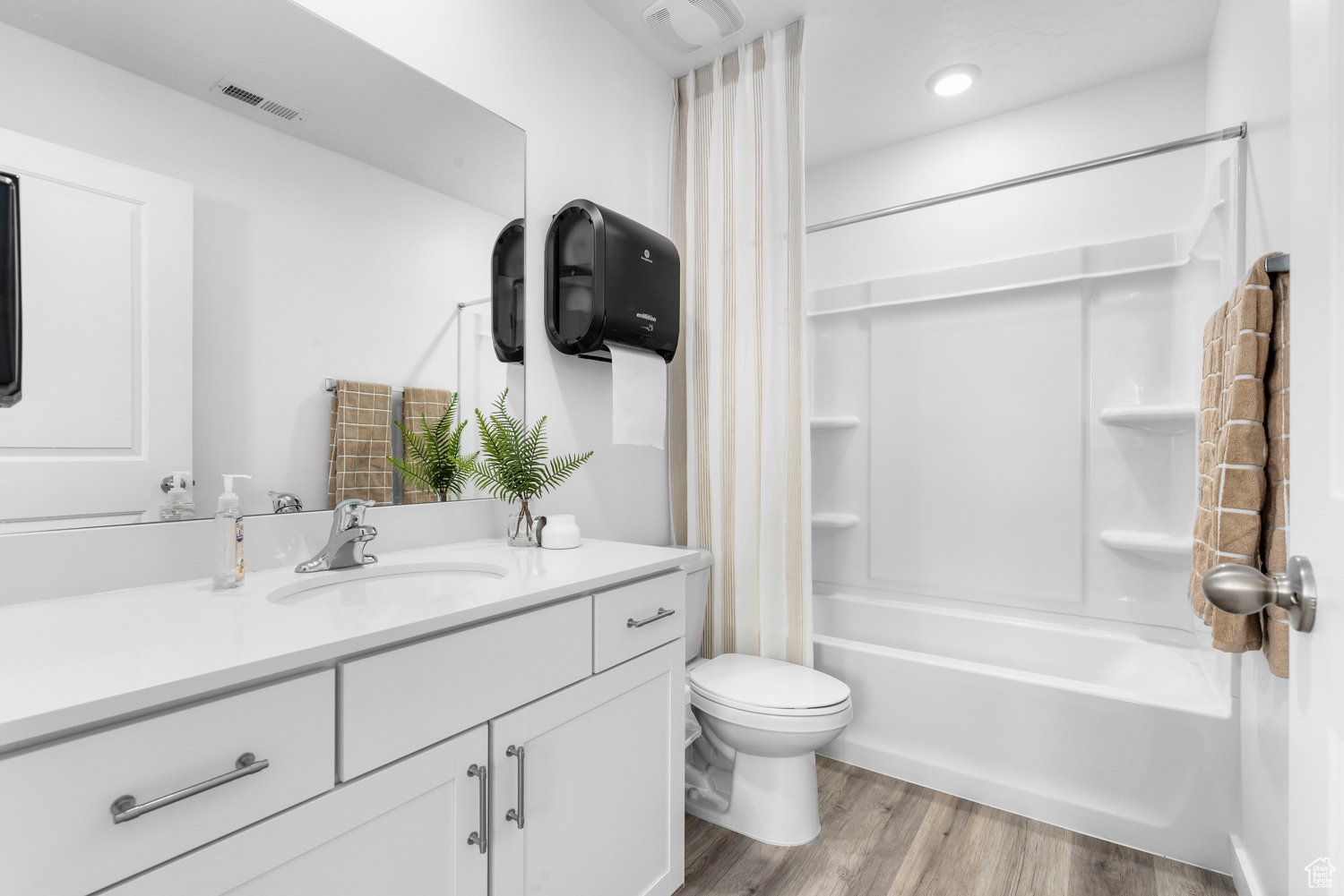 Full bathroom with toilet, vanity, shower / bath combination with curtain, and hardwood / wood-style flooring