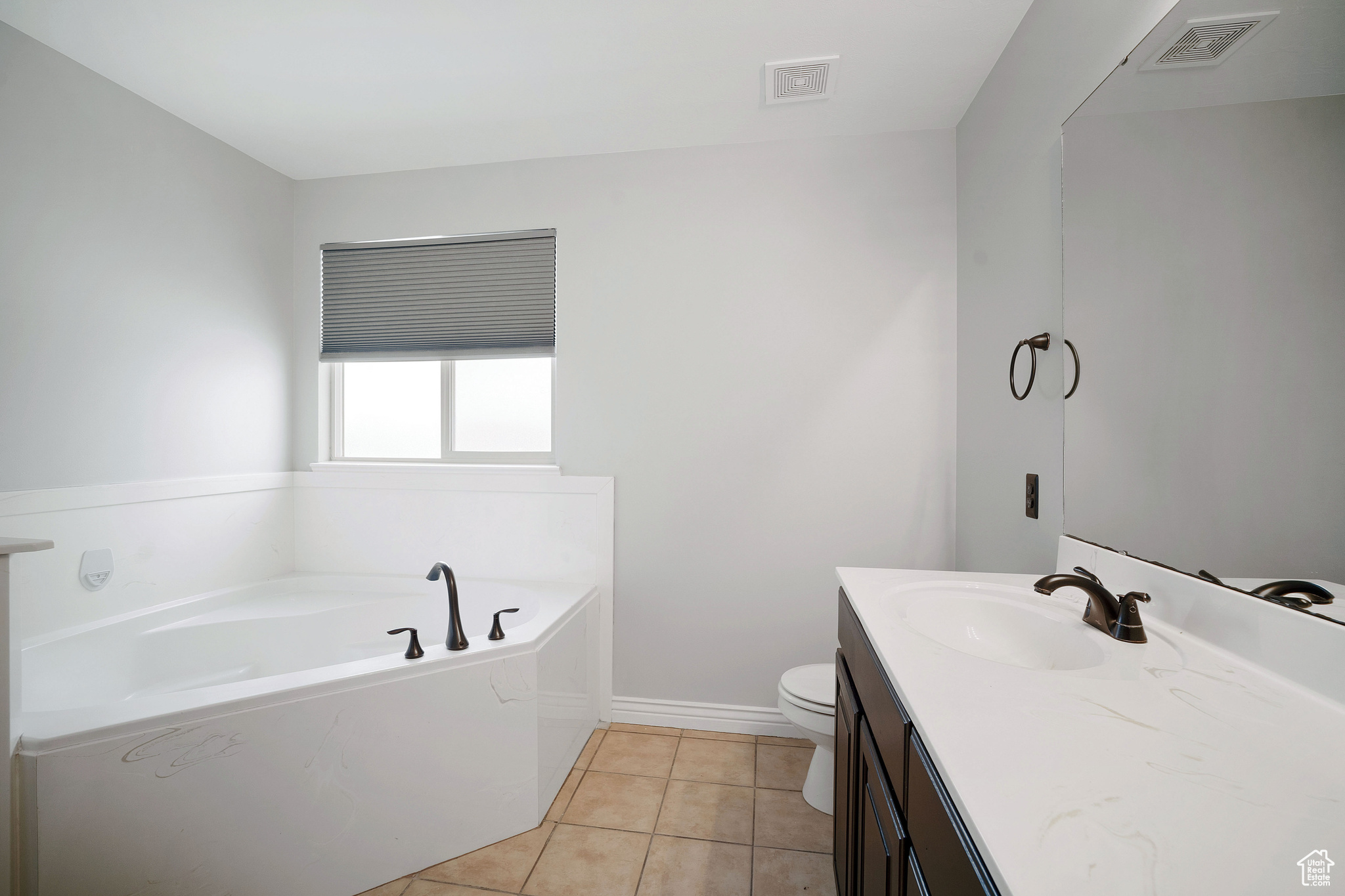 Bathroom featuring vanity, tile patterned flooring, a bathtub, and toilet