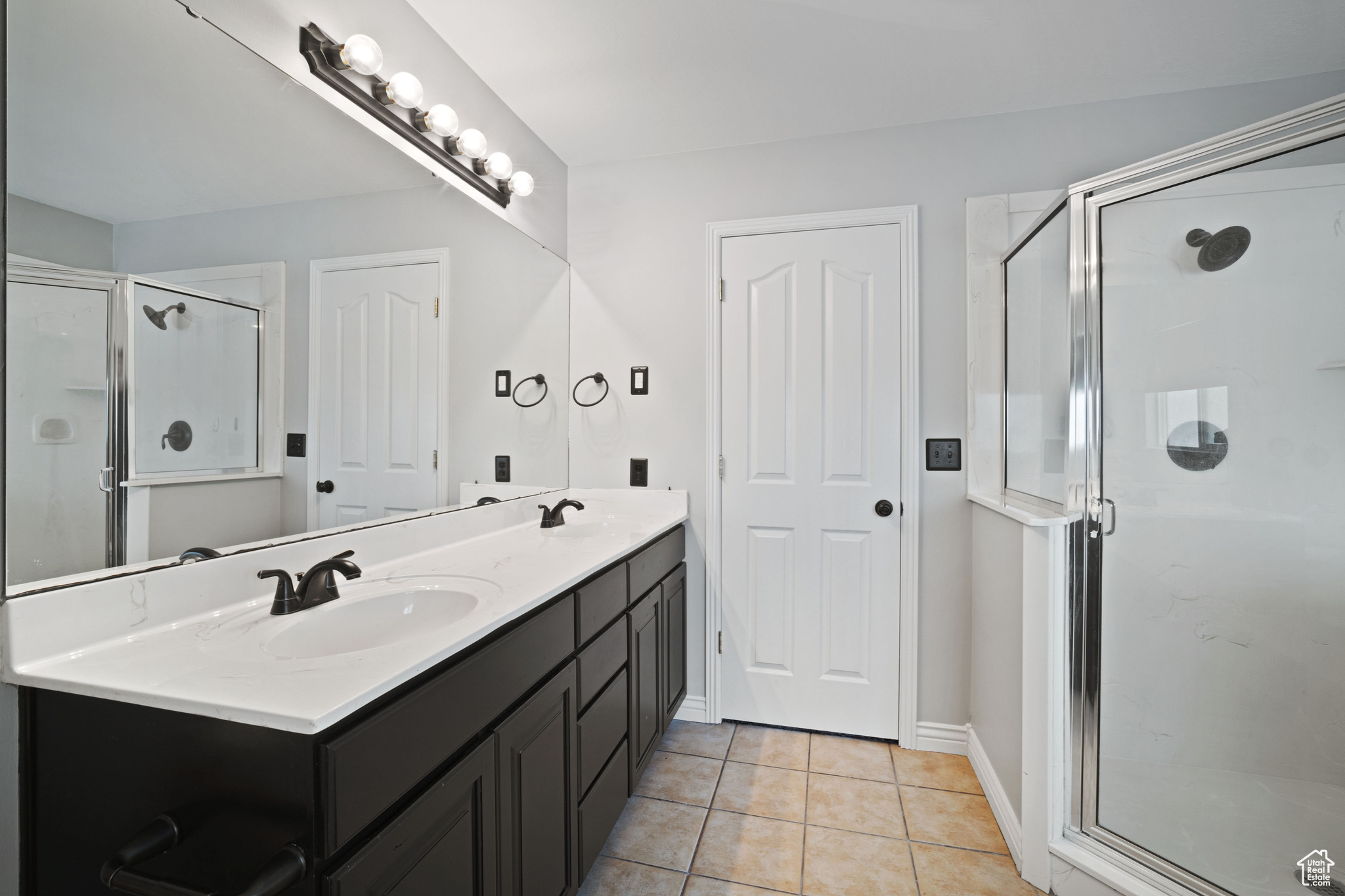 Bathroom featuring tile patterned flooring, vanity, and an enclosed shower