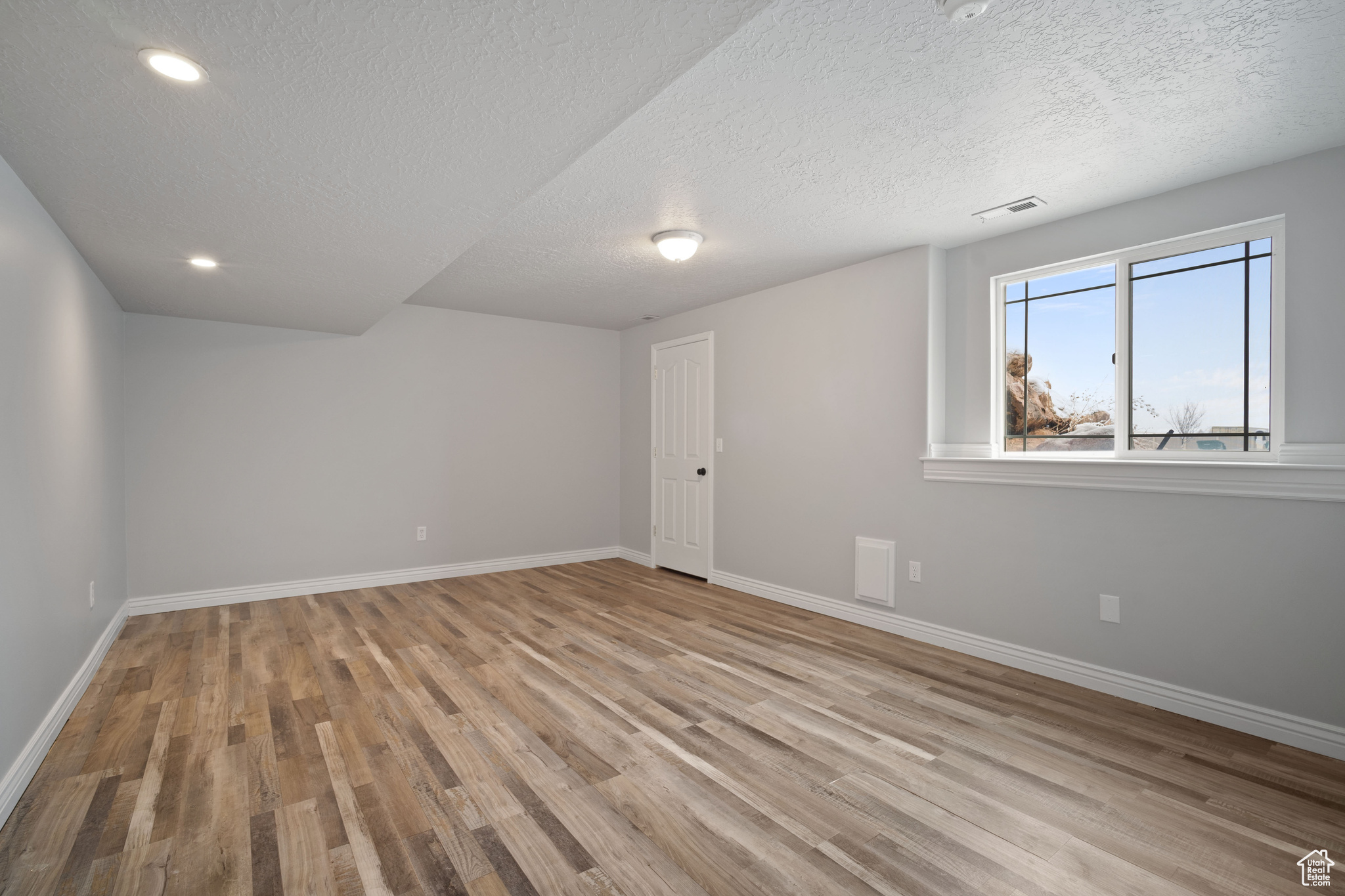 Empty room featuring a textured ceiling and light hardwood / wood-style flooring