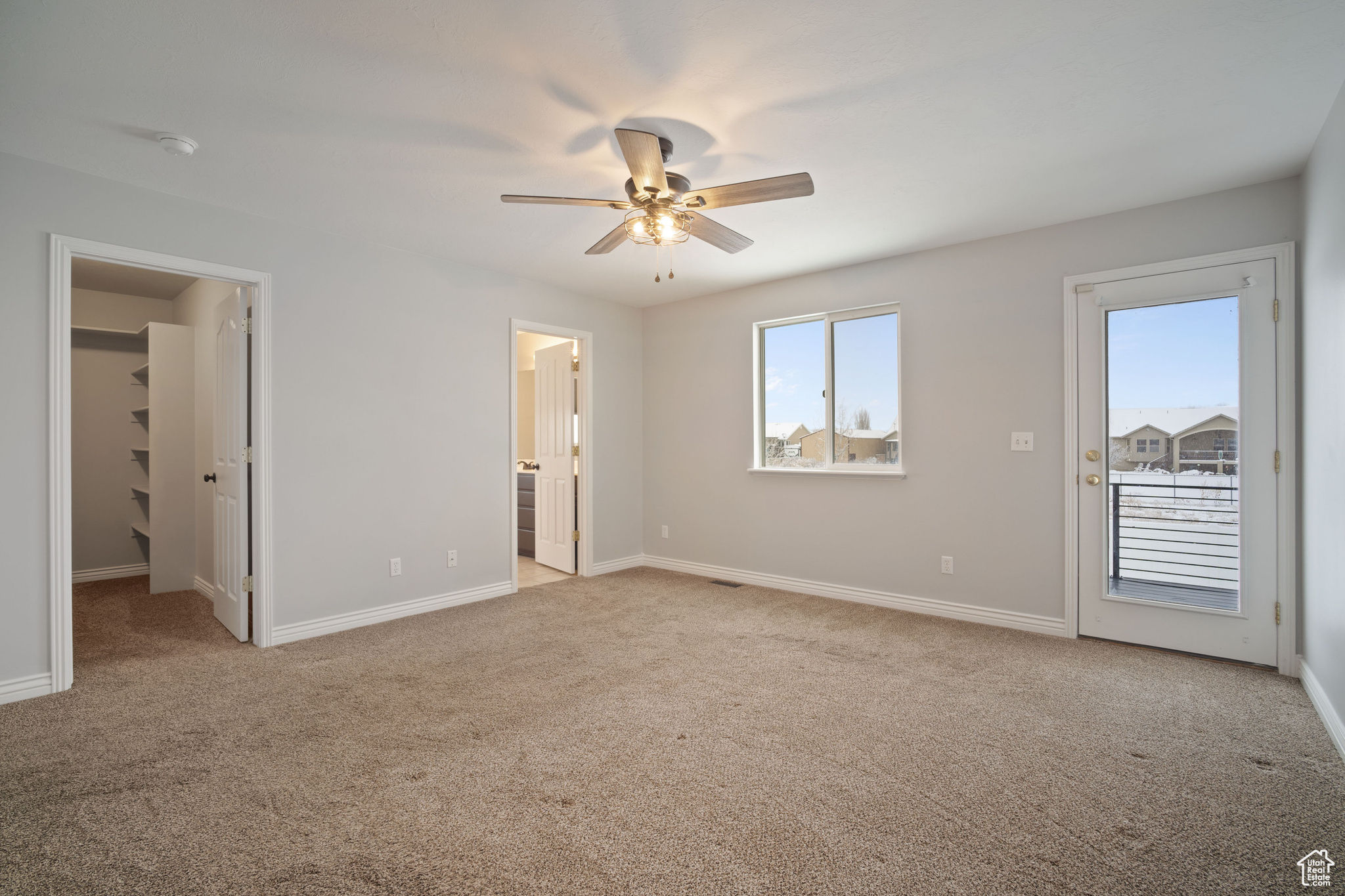 Unfurnished bedroom with ceiling fan, a spacious closet, light carpet, and connected bathroom