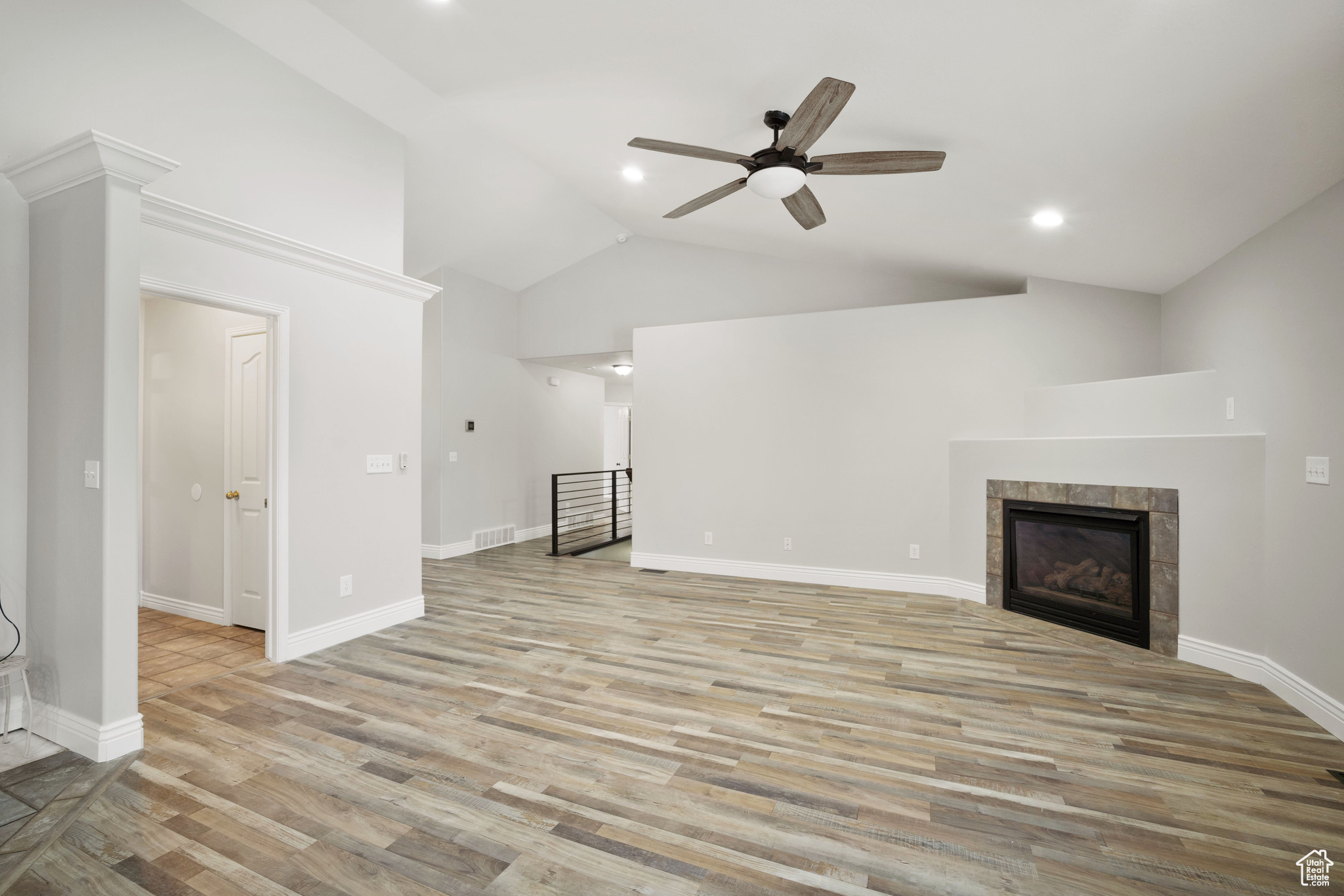 Unfurnished living room with ceiling fan, a fireplace, high vaulted ceiling, and light wood-type flooring