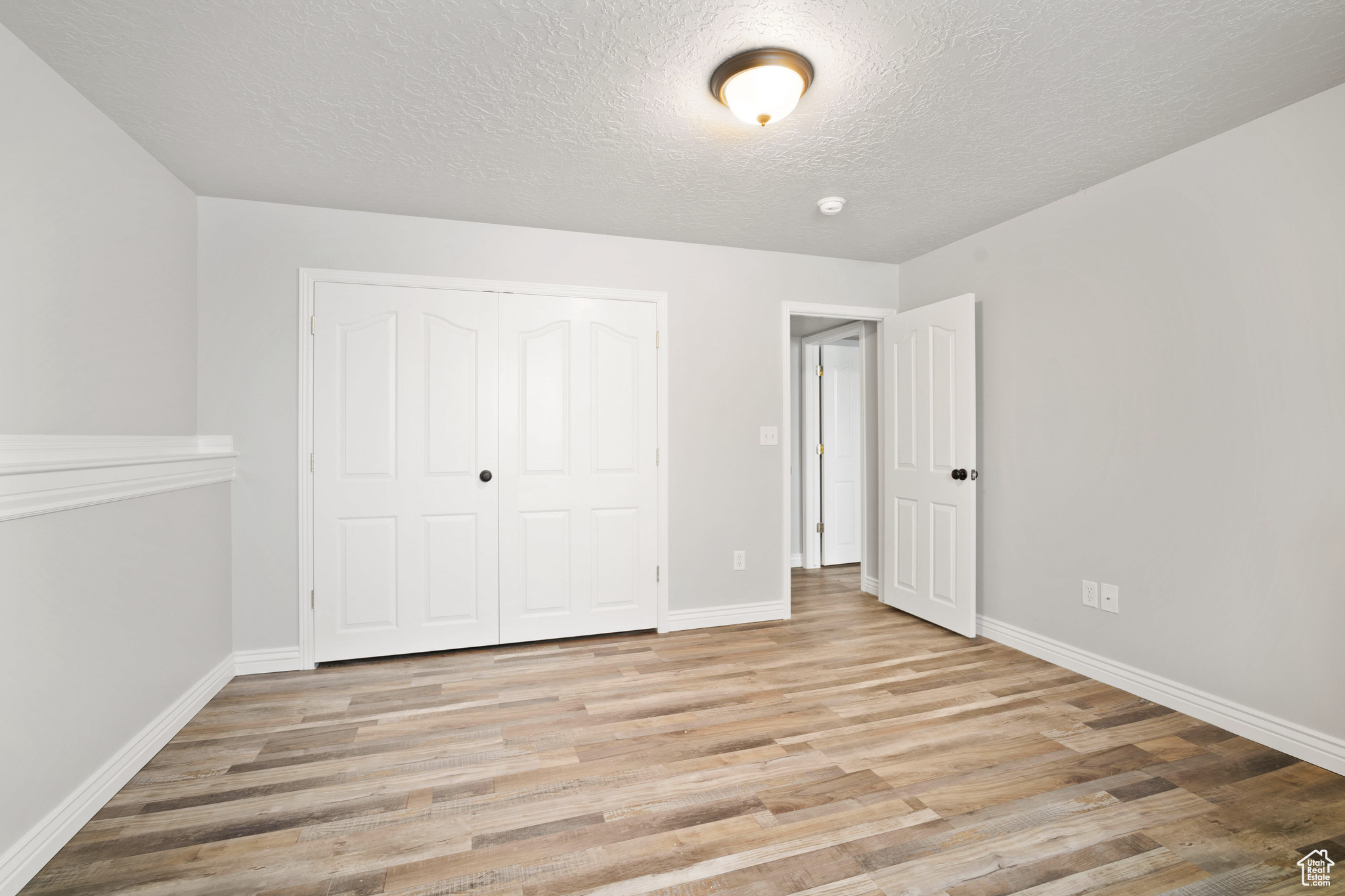 Unfurnished bedroom with a textured ceiling, light hardwood / wood-style floors, and a closet