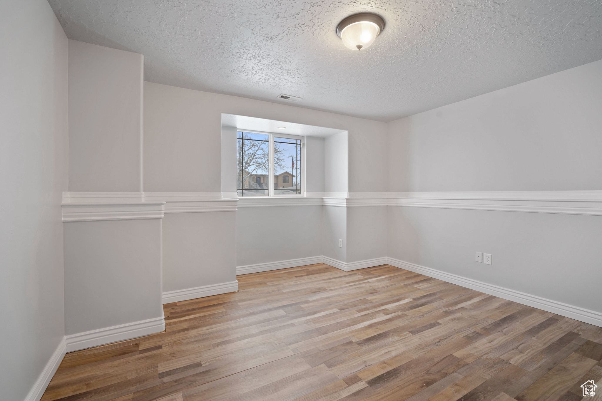 Spare room featuring light hardwood / wood-style floors and a textured ceiling