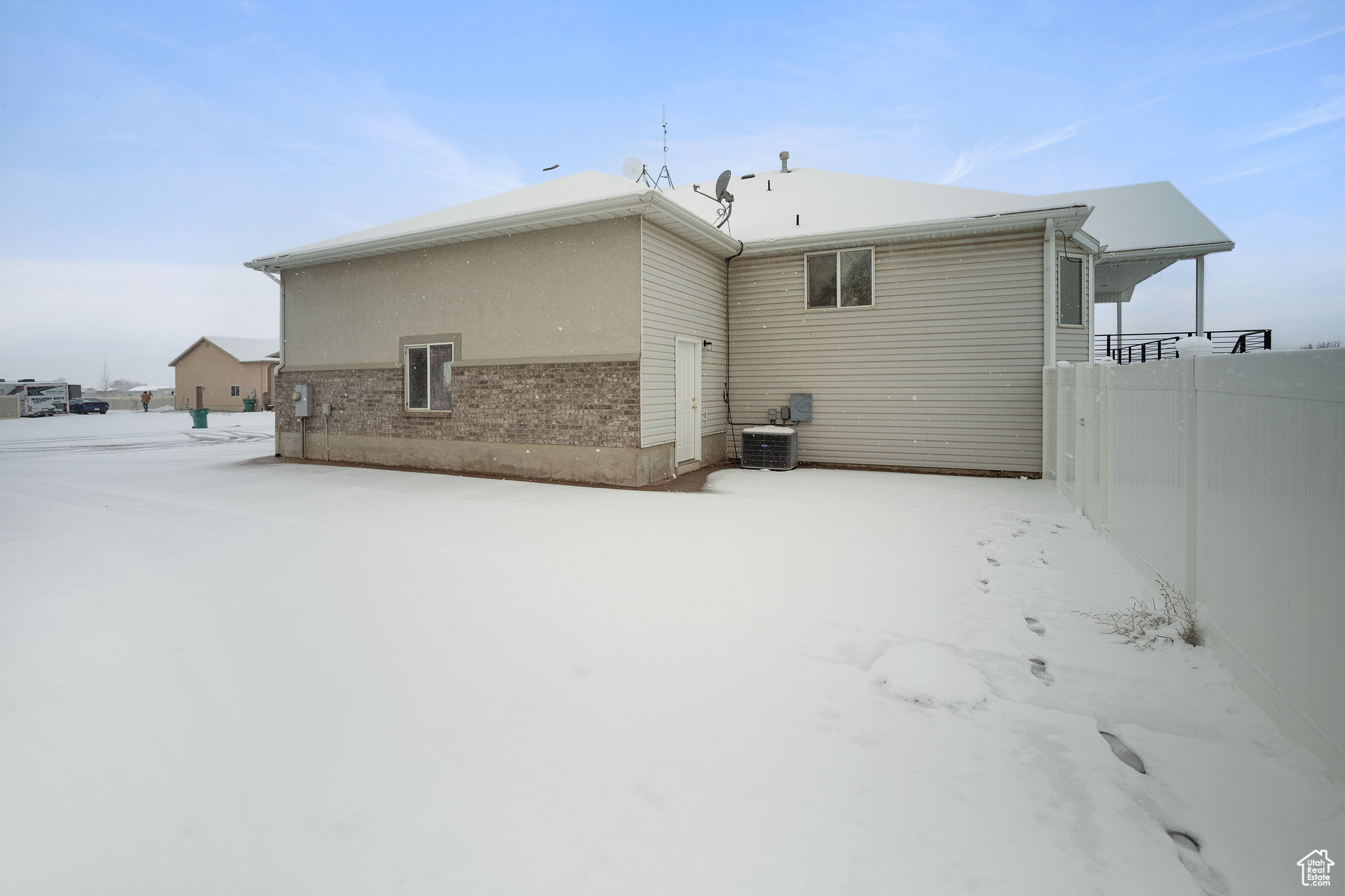 Snow covered rear of property featuring central AC unit