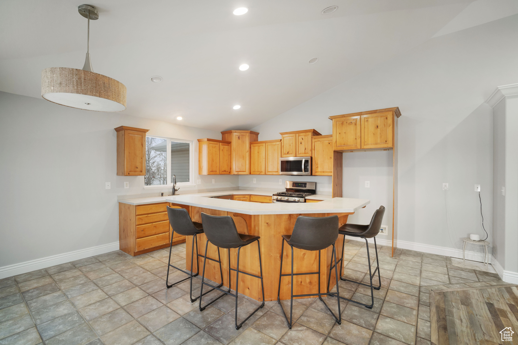 Kitchen featuring a breakfast bar, a center island, sink, vaulted ceiling, and appliances with stainless steel finishes