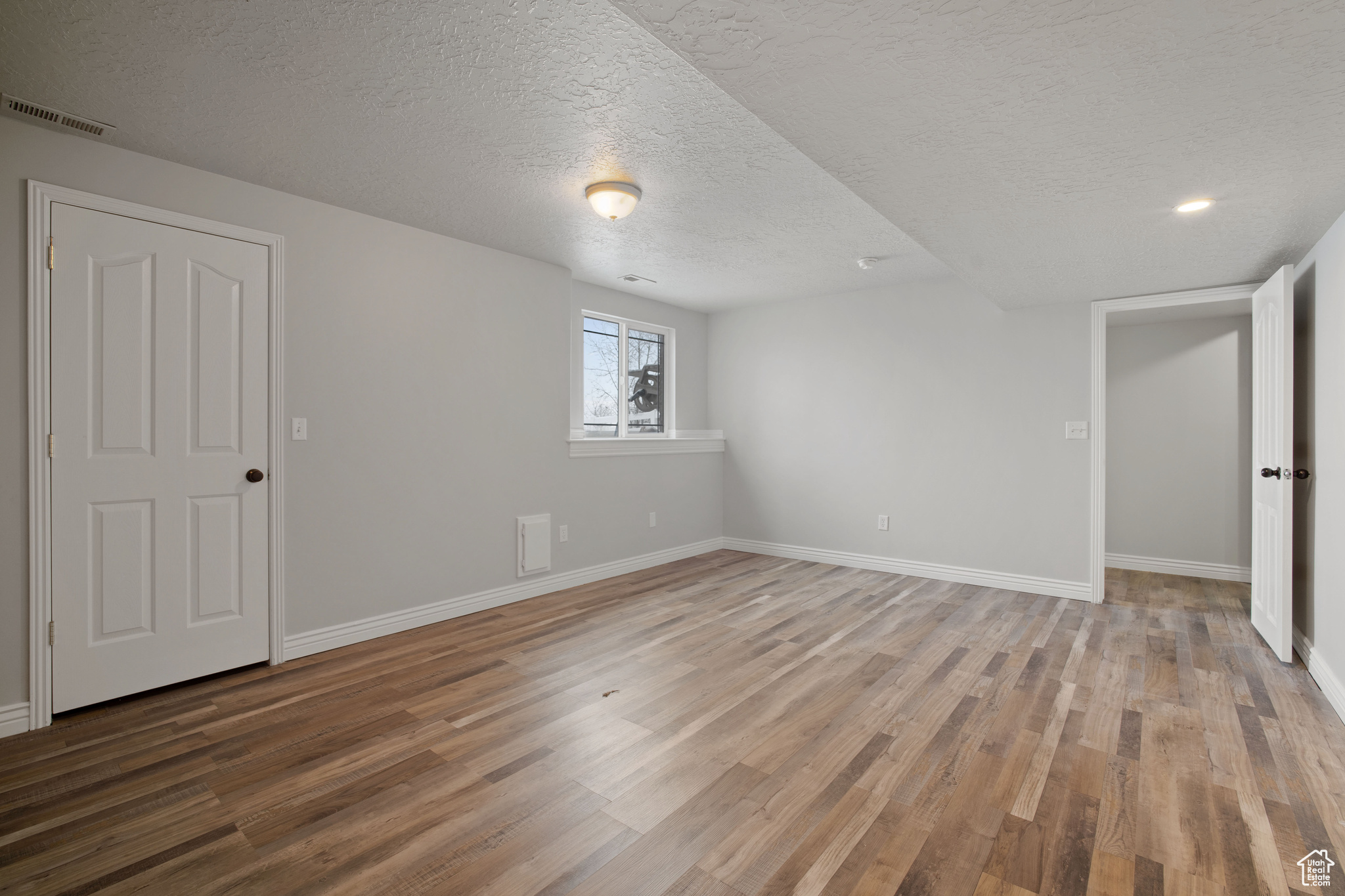 Unfurnished bedroom featuring hardwood / wood-style floors and a textured ceiling