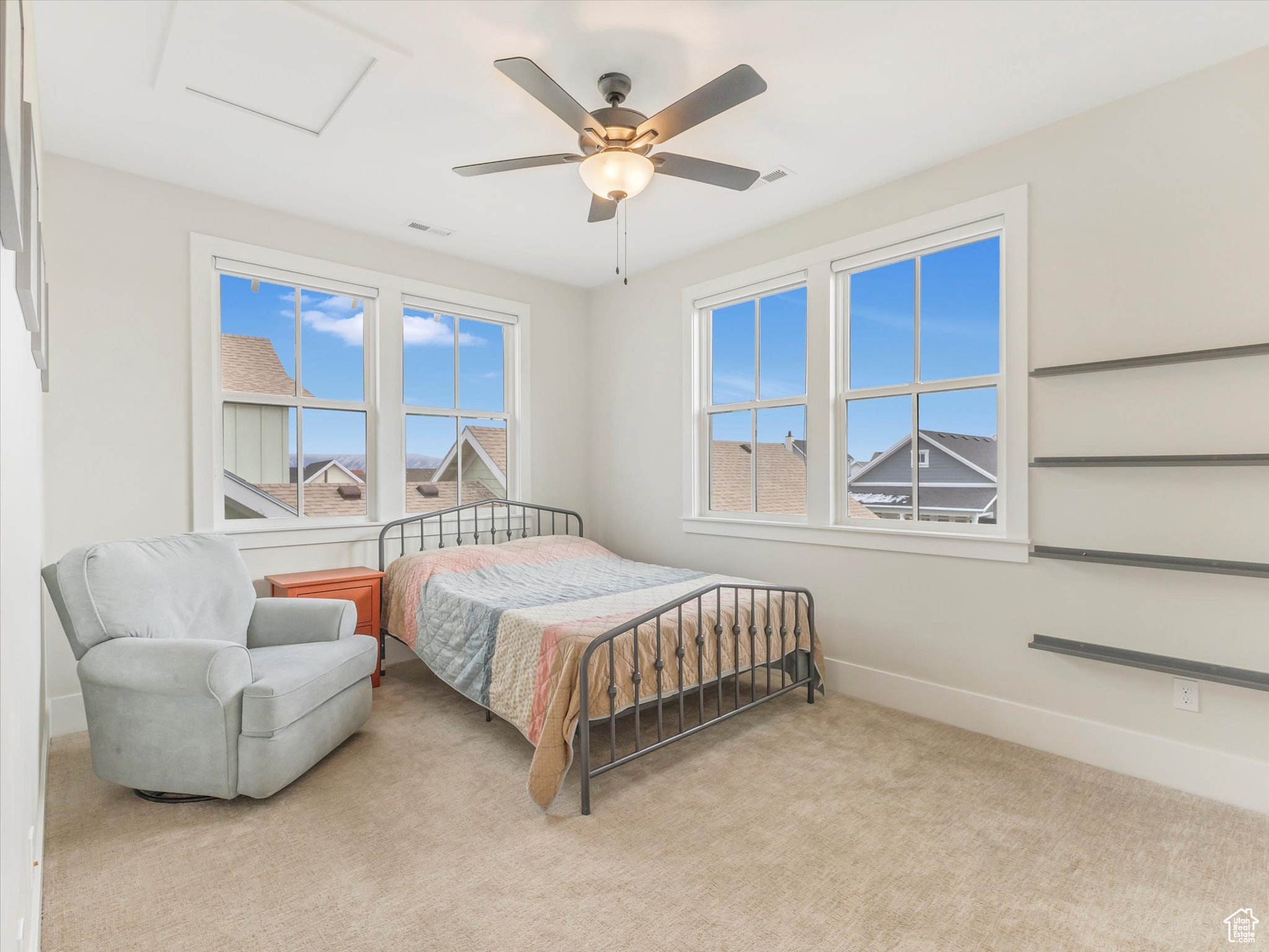 Bedroom with light carpet, multiple windows, and ceiling fan