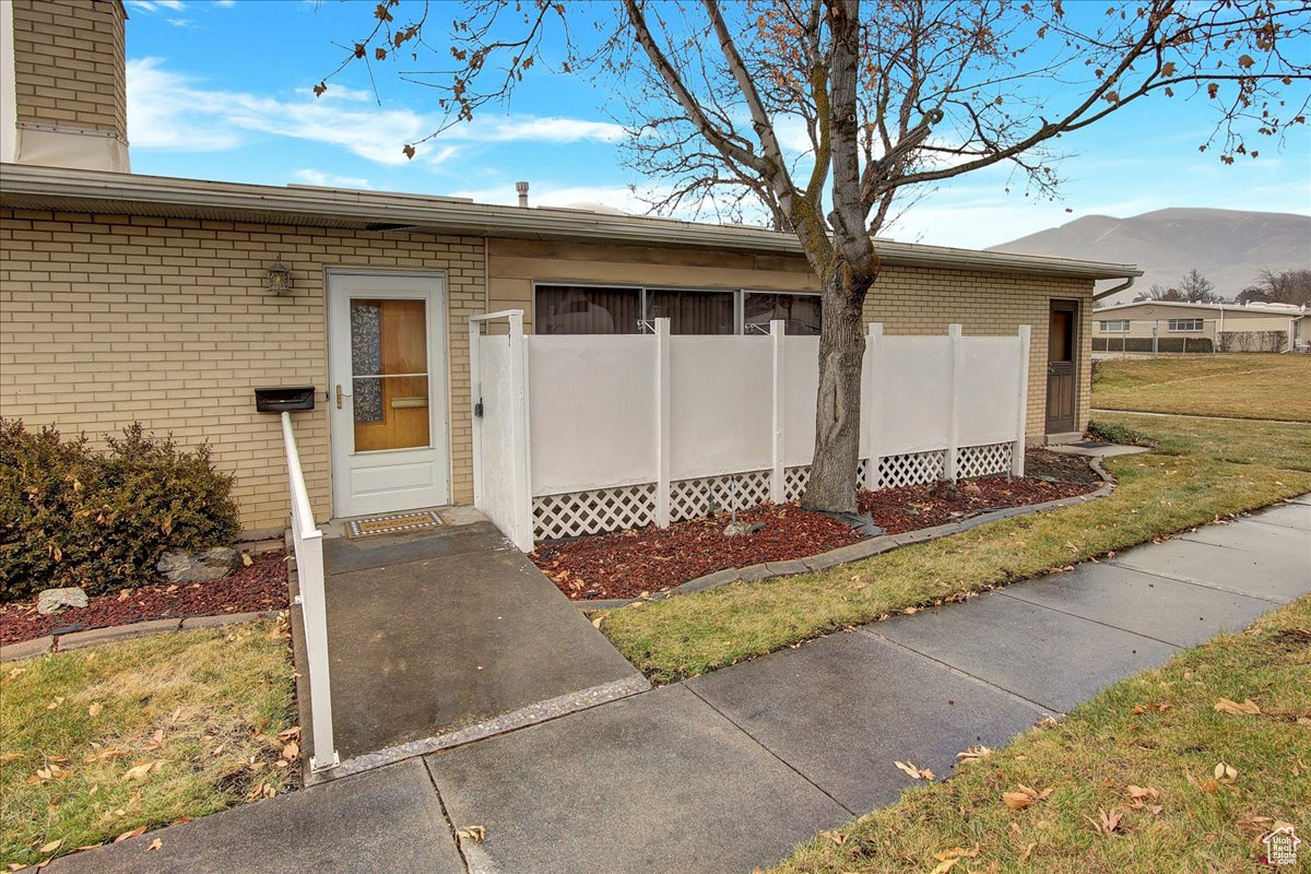 View of exterior entry featuring a mountain view and a yard