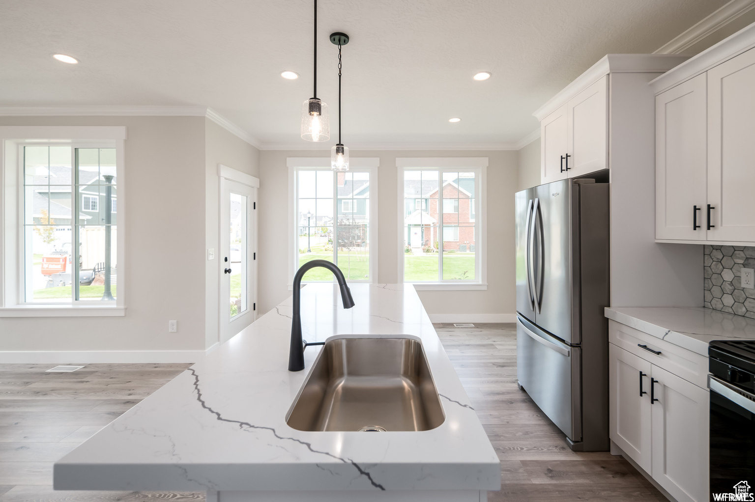 Kitchen with tasteful backsplash, a kitchen island with sink, pendant lighting, and appliances with stainless steel finishes