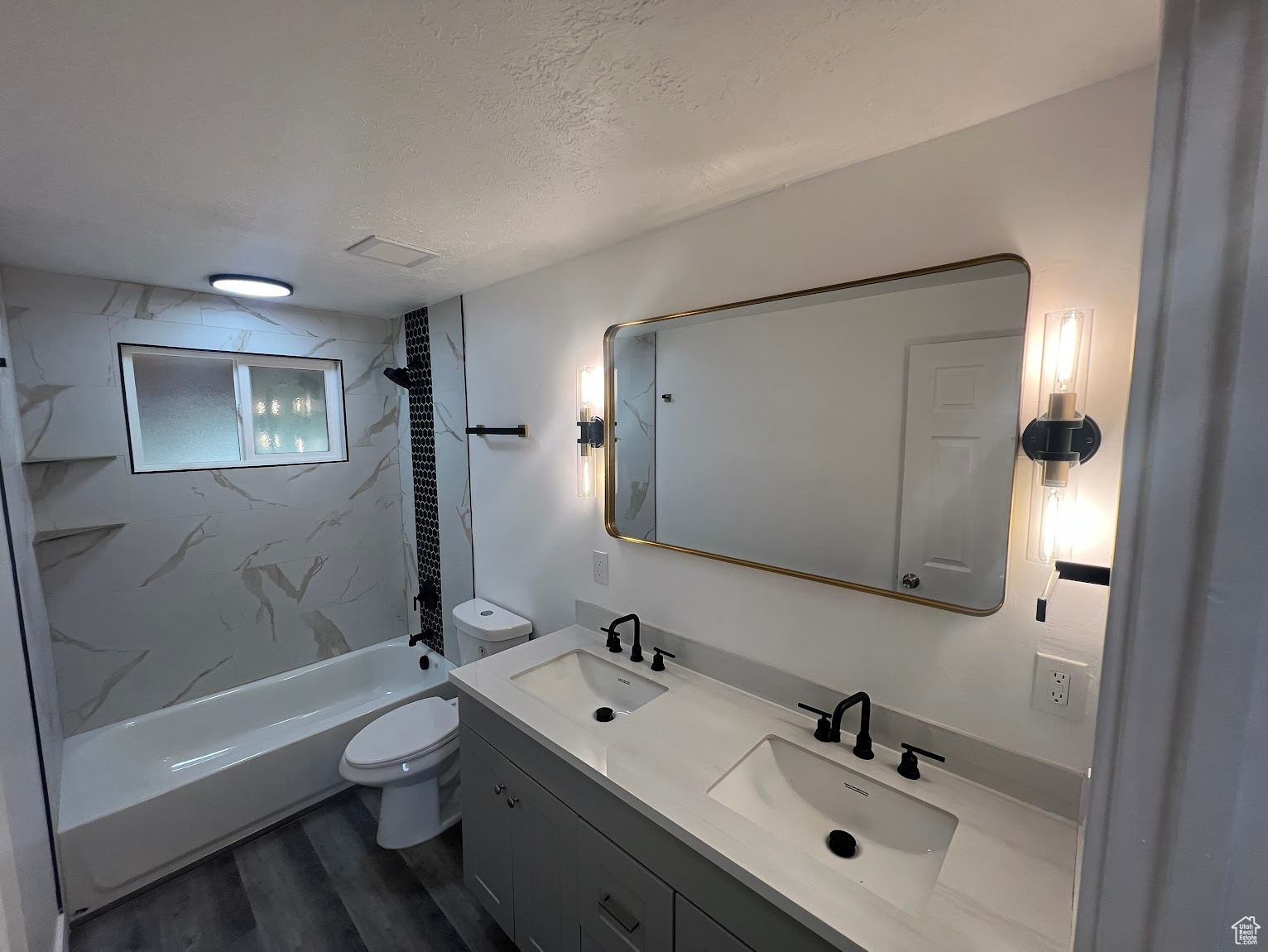 Full bathroom with vanity, a textured ceiling, hardwood / wood-style floors, toilet, and tiled shower / bath