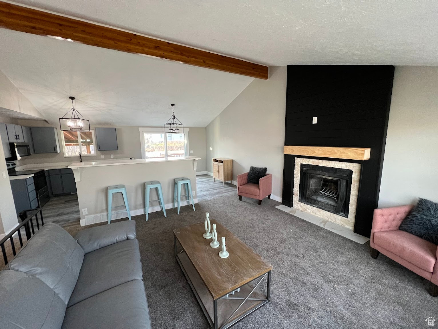 Carpeted living room featuring lofted ceiling with beams, sink, and a chandelier