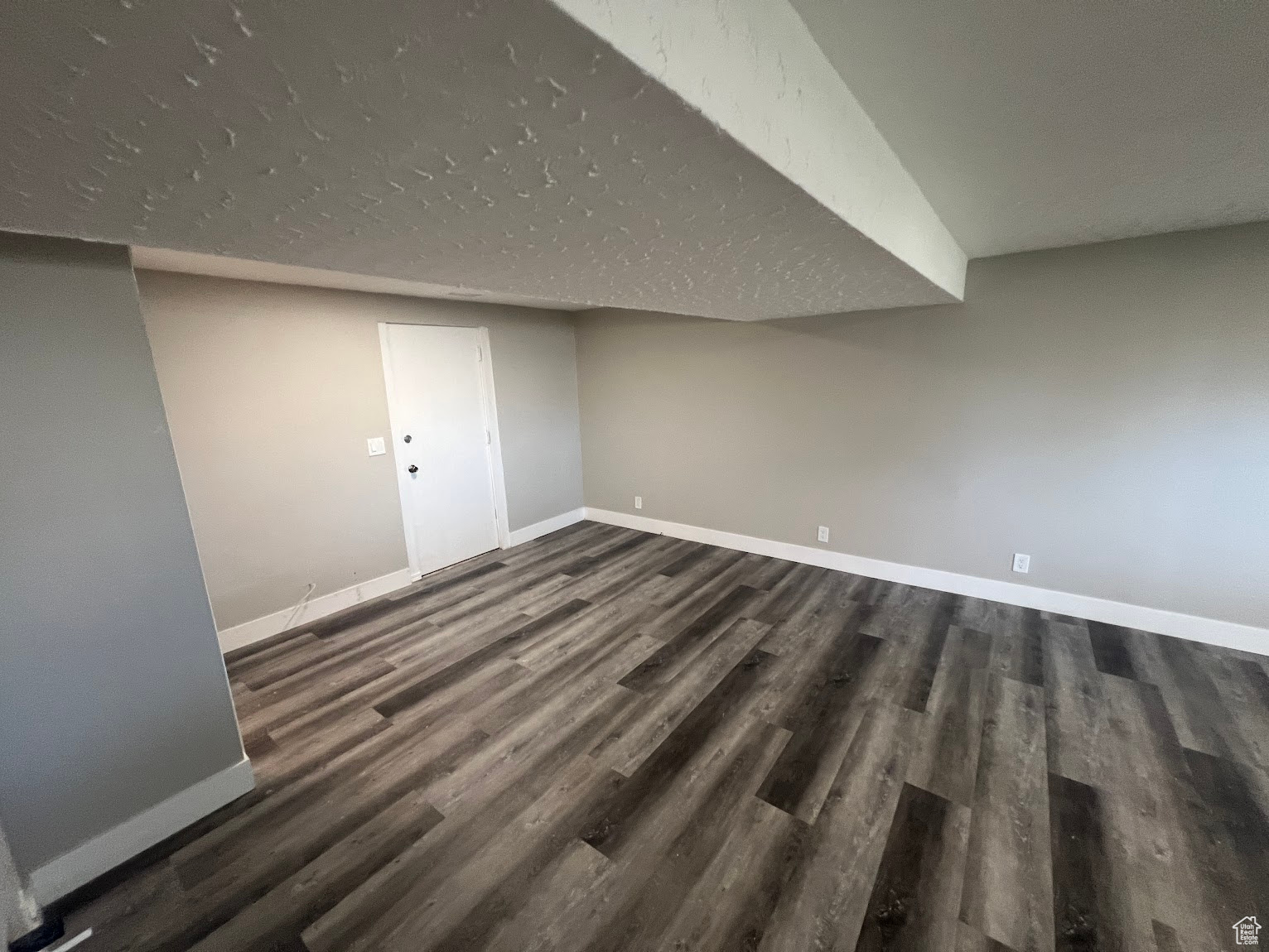 Basement with a textured ceiling and dark hardwood / wood-style floors