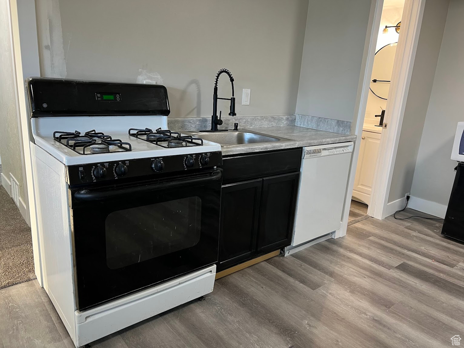 Kitchen with white appliances, sink, and light hardwood / wood-style flooring