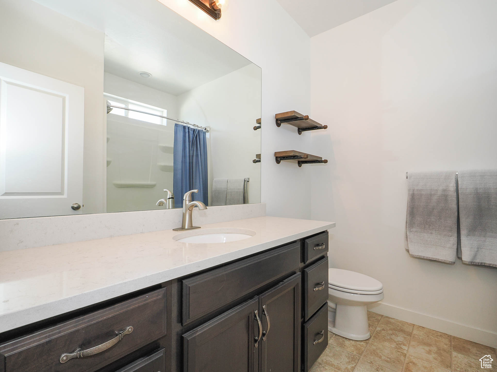 Bathroom with toilet, vanity, and a shower with shower curtain