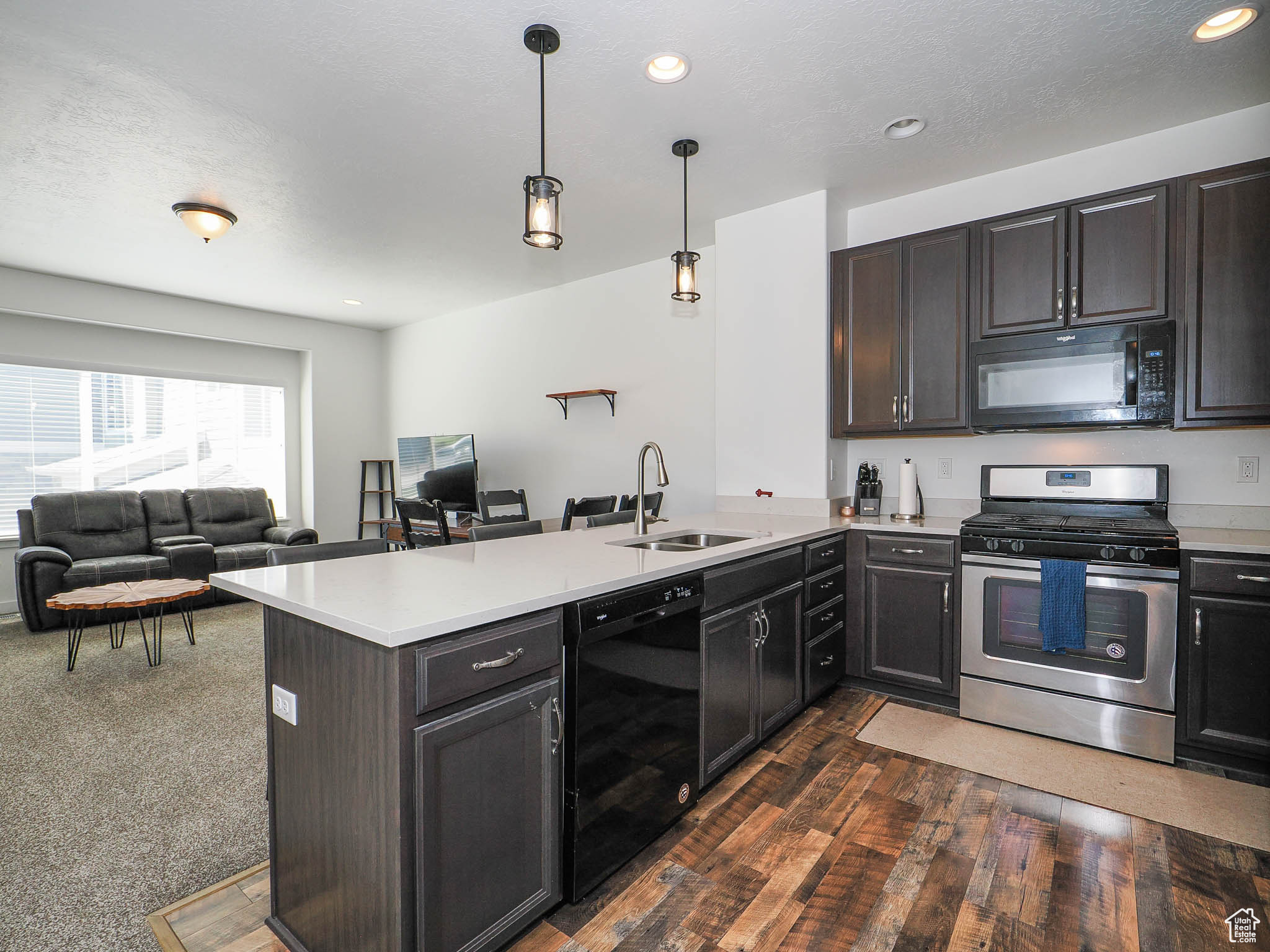 Kitchen featuring kitchen peninsula, sink, decorative light fixtures, and black appliances