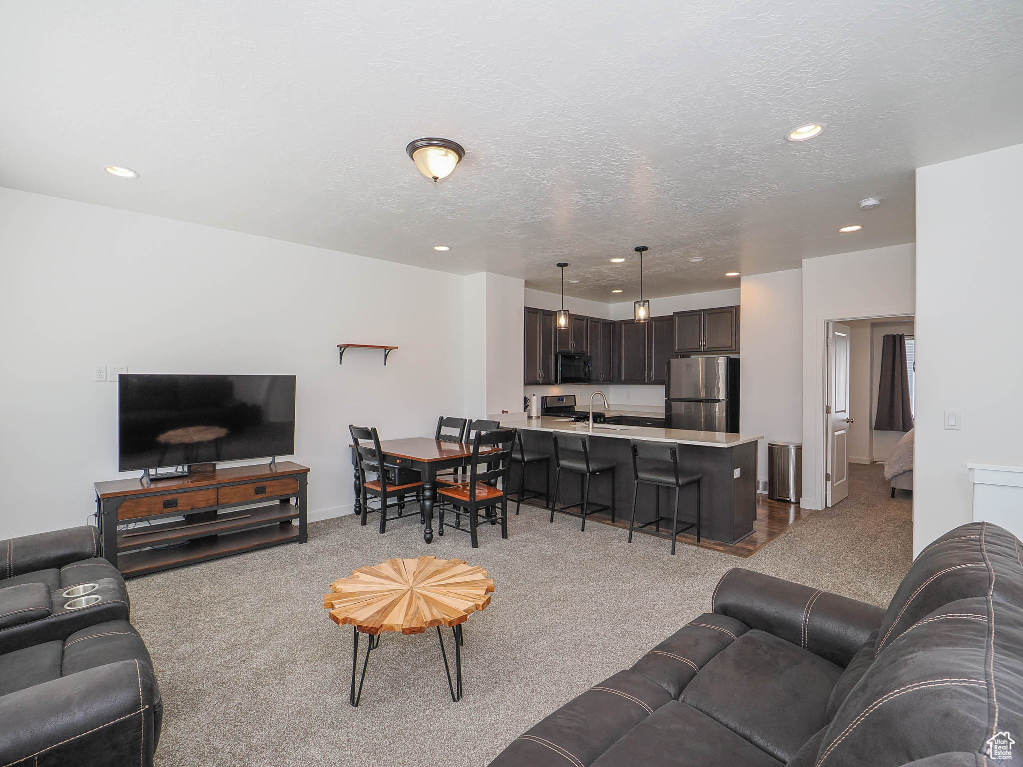 Carpeted living room featuring sink and a textured ceiling