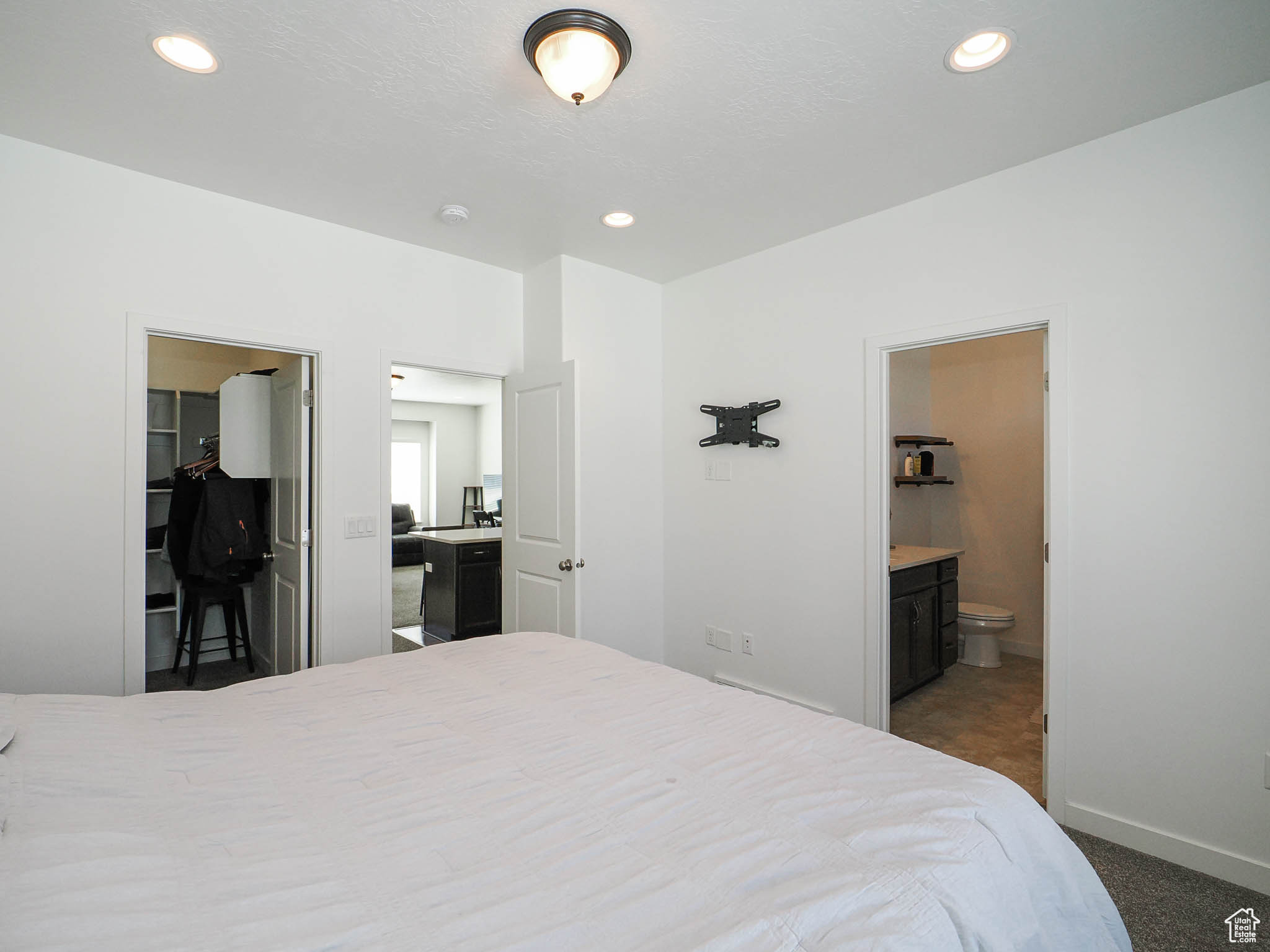 Bedroom featuring a walk in closet, connected bathroom, dark carpet, and a closet