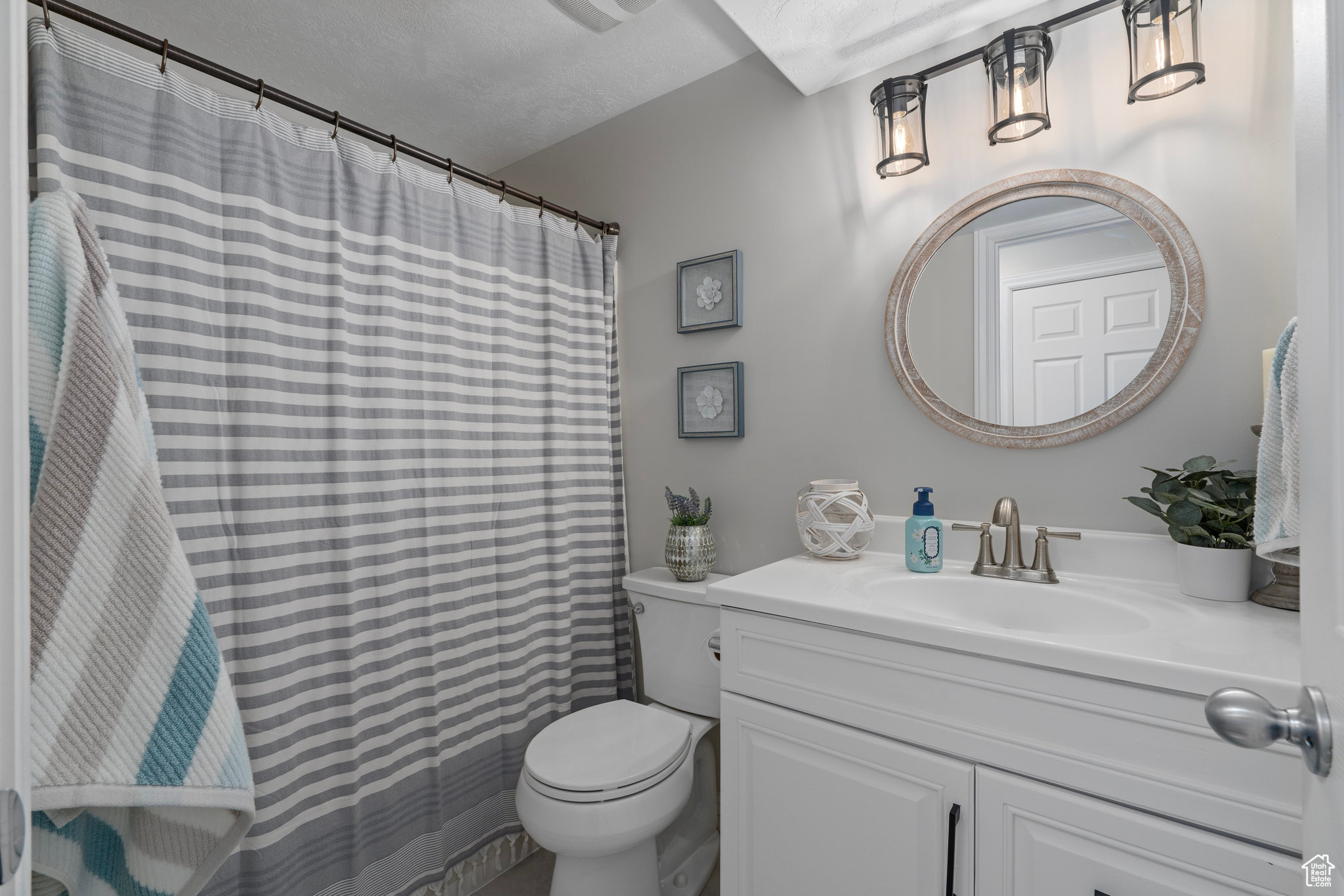 Bathroom with a textured ceiling, vanity, and toilet