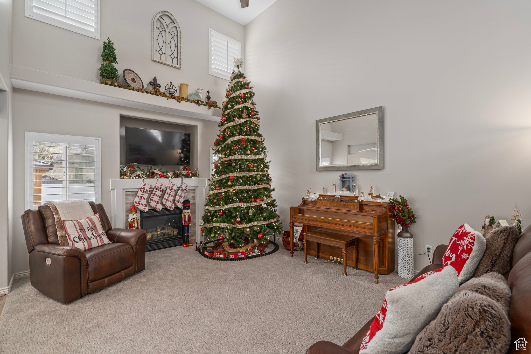 Carpeted living room featuring a tile fireplace, a wealth of natural light, and a towering ceiling