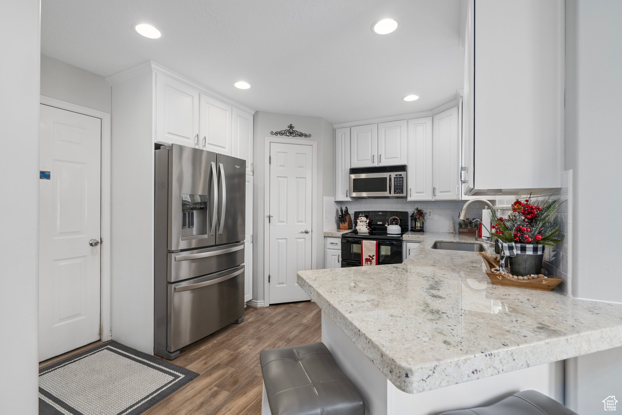 Kitchen featuring a breakfast bar, white cabinets, sink, appliances with stainless steel finishes, and kitchen peninsula