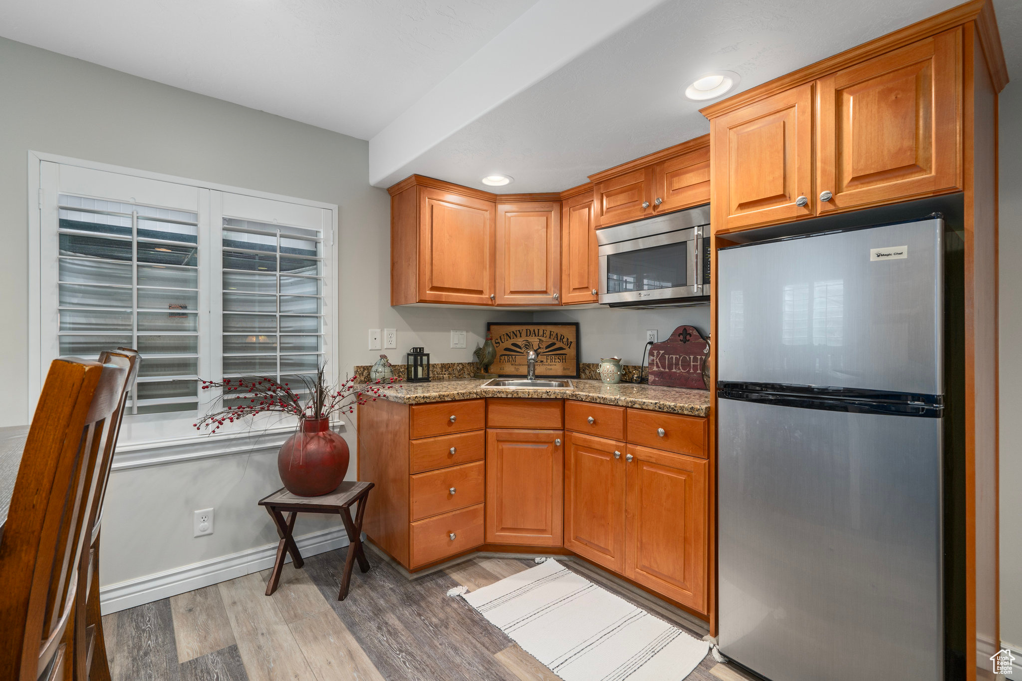 Kitchen featuring hardwood / wood-style floors, light stone countertops, sink, and appliances with stainless steel finishes