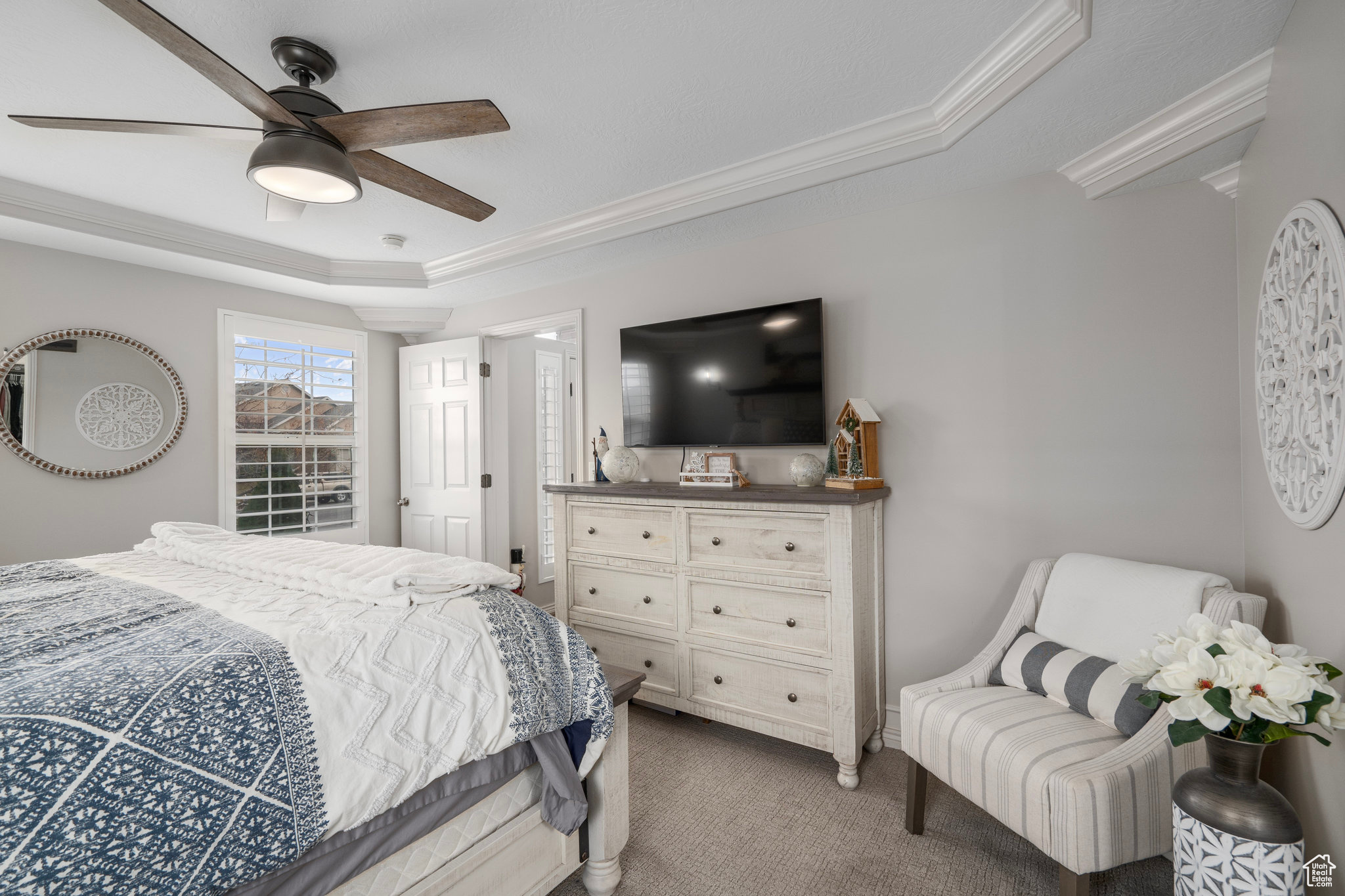 Carpeted bedroom featuring a tray ceiling, ceiling fan, and ornamental molding