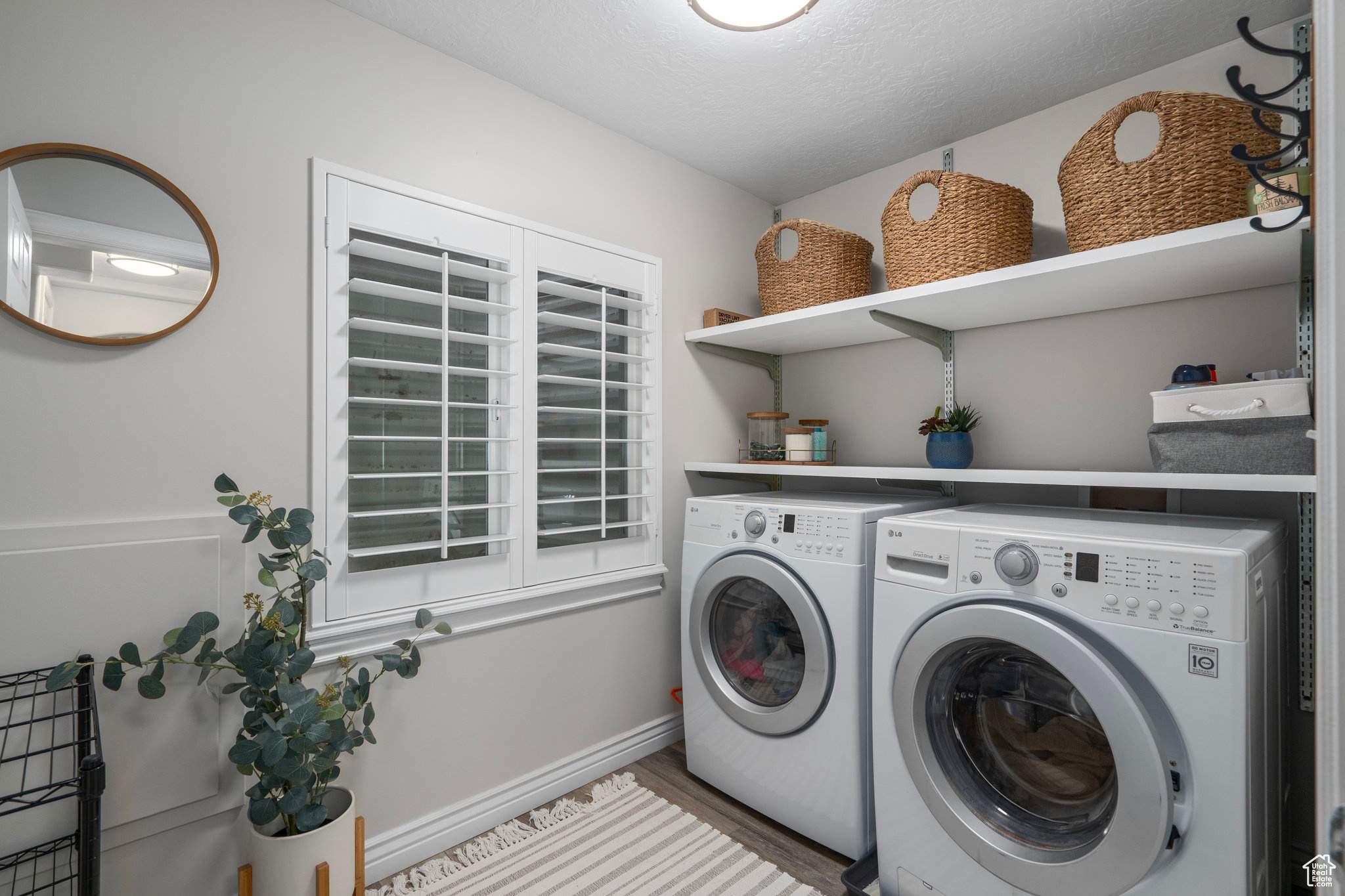 Clothes washing area featuring wood-type flooring, a textured ceiling, and washer and clothes dryer