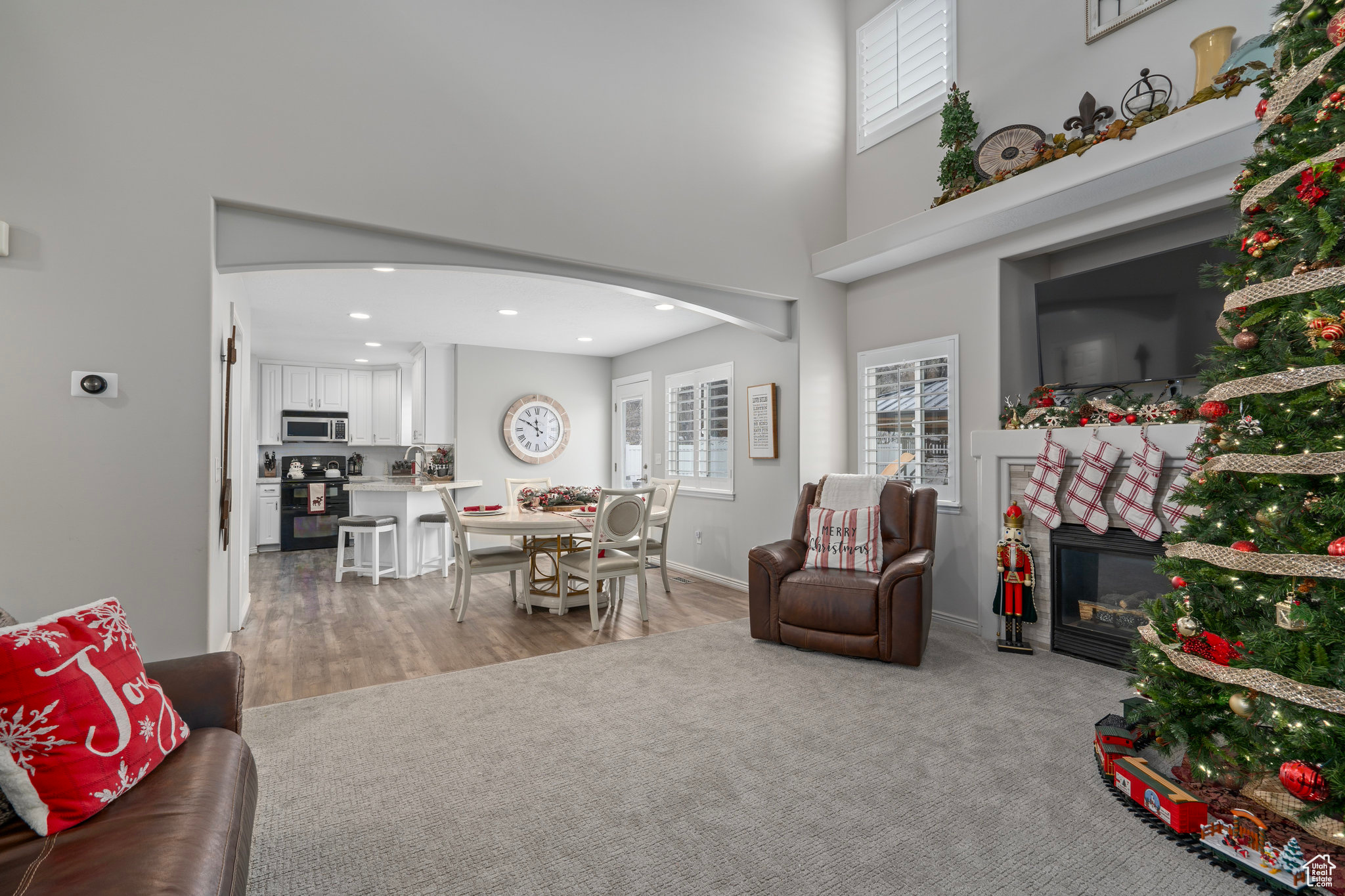 Carpeted living room with a towering ceiling and a healthy amount of sunlight