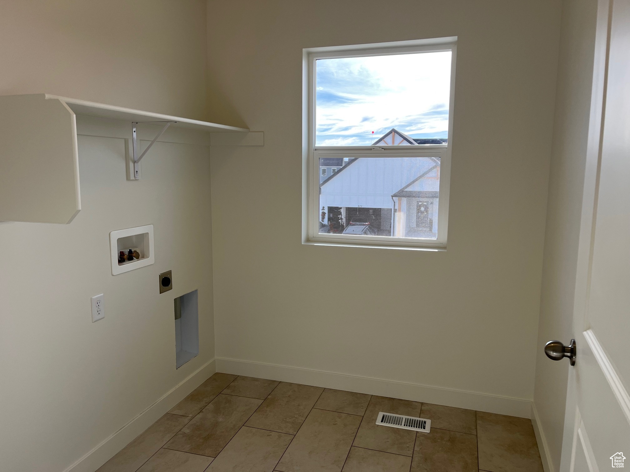 Clothes washing area with washer hookup, electric dryer hookup, and light tile patterned flooring