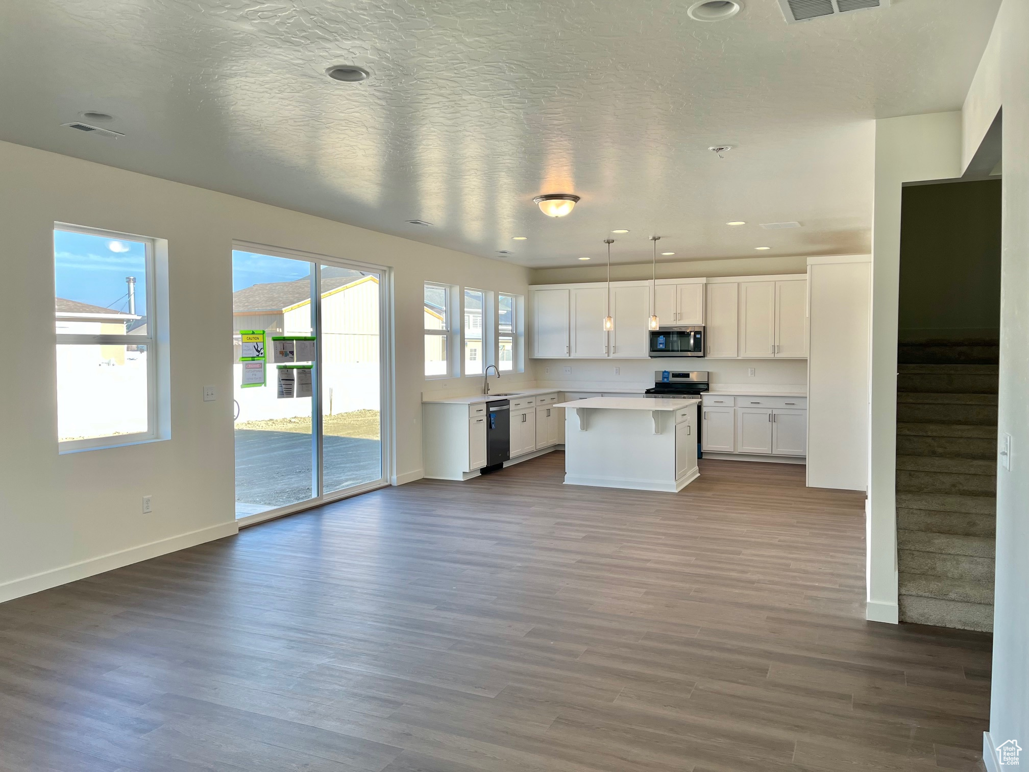 Kitchen with sink, pendant lighting, dishwasher, white cabinets, and a kitchen island