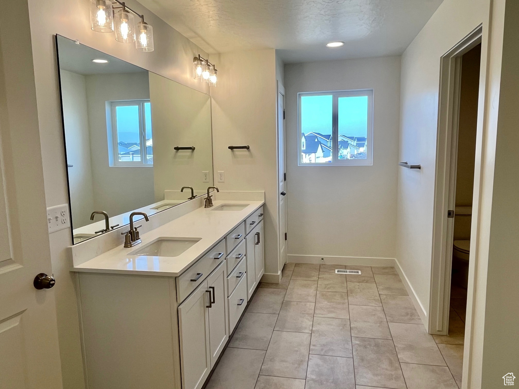 Bathroom featuring vanity, a textured ceiling, tile patterned floors, and a healthy amount of sunlight