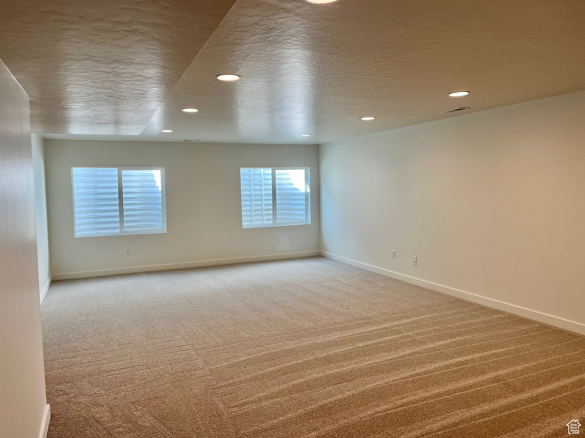 Empty room featuring a textured ceiling and light colored carpet