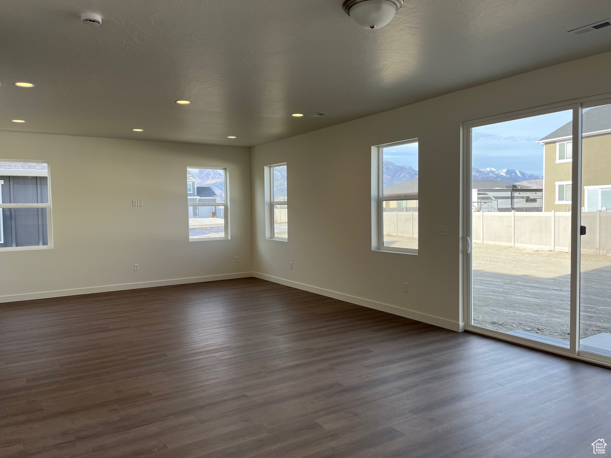 Unfurnished room featuring a wealth of natural light, a mountain view, and dark wood-type flooring