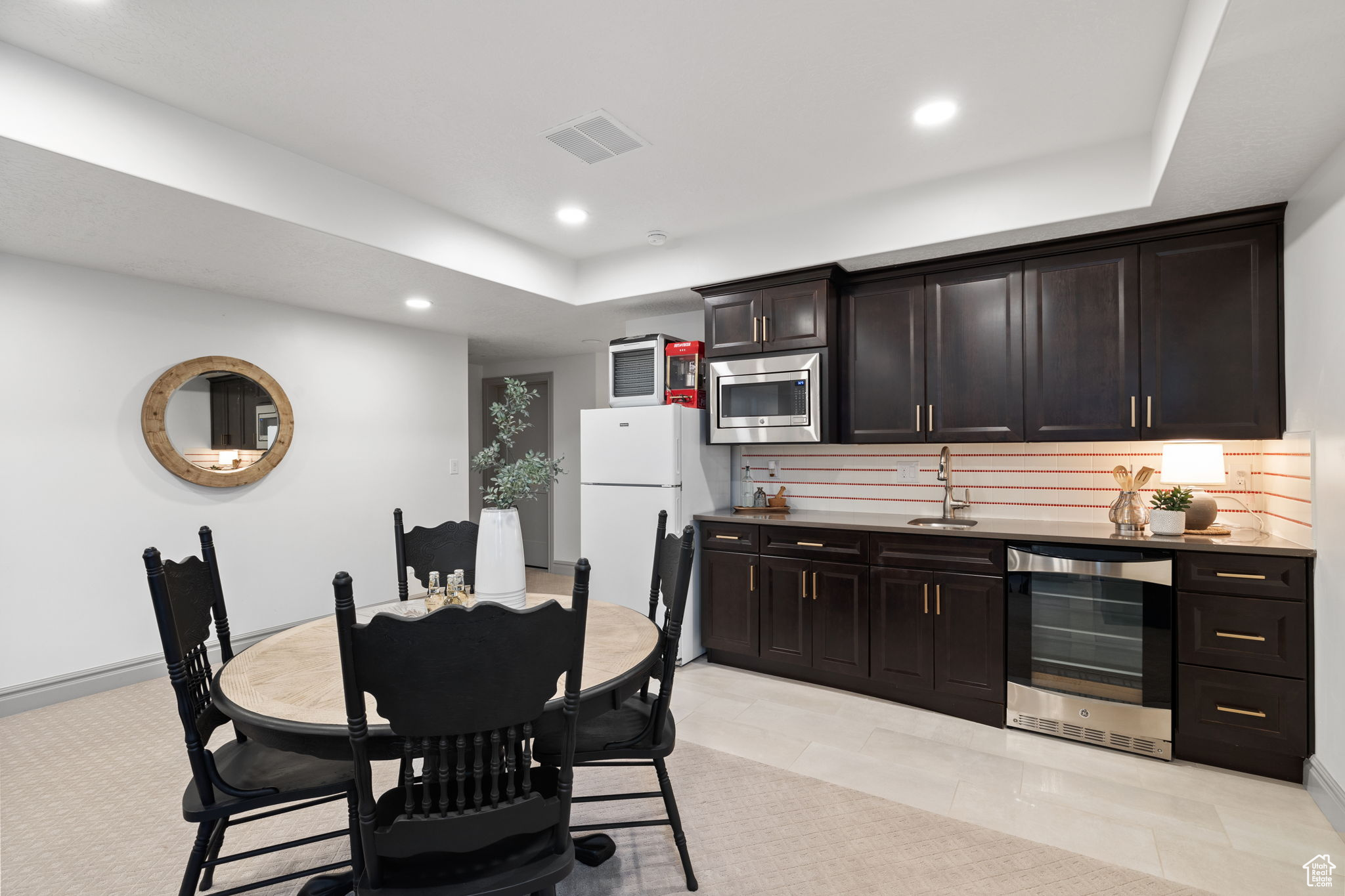 Kitchen featuring dark brown cabinetry, stainless steel microwave, sink, wine cooler, and white fridge