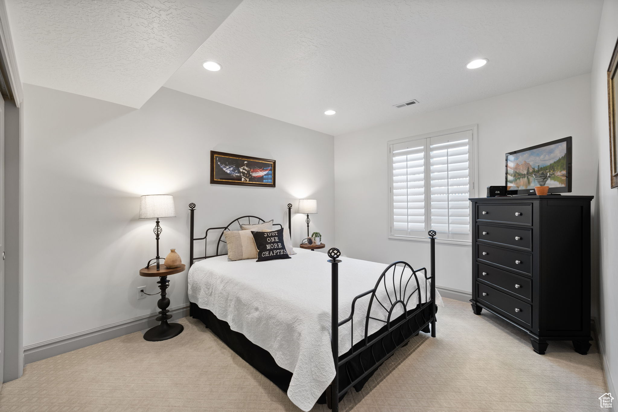 Bedroom with a textured ceiling and light colored carpet