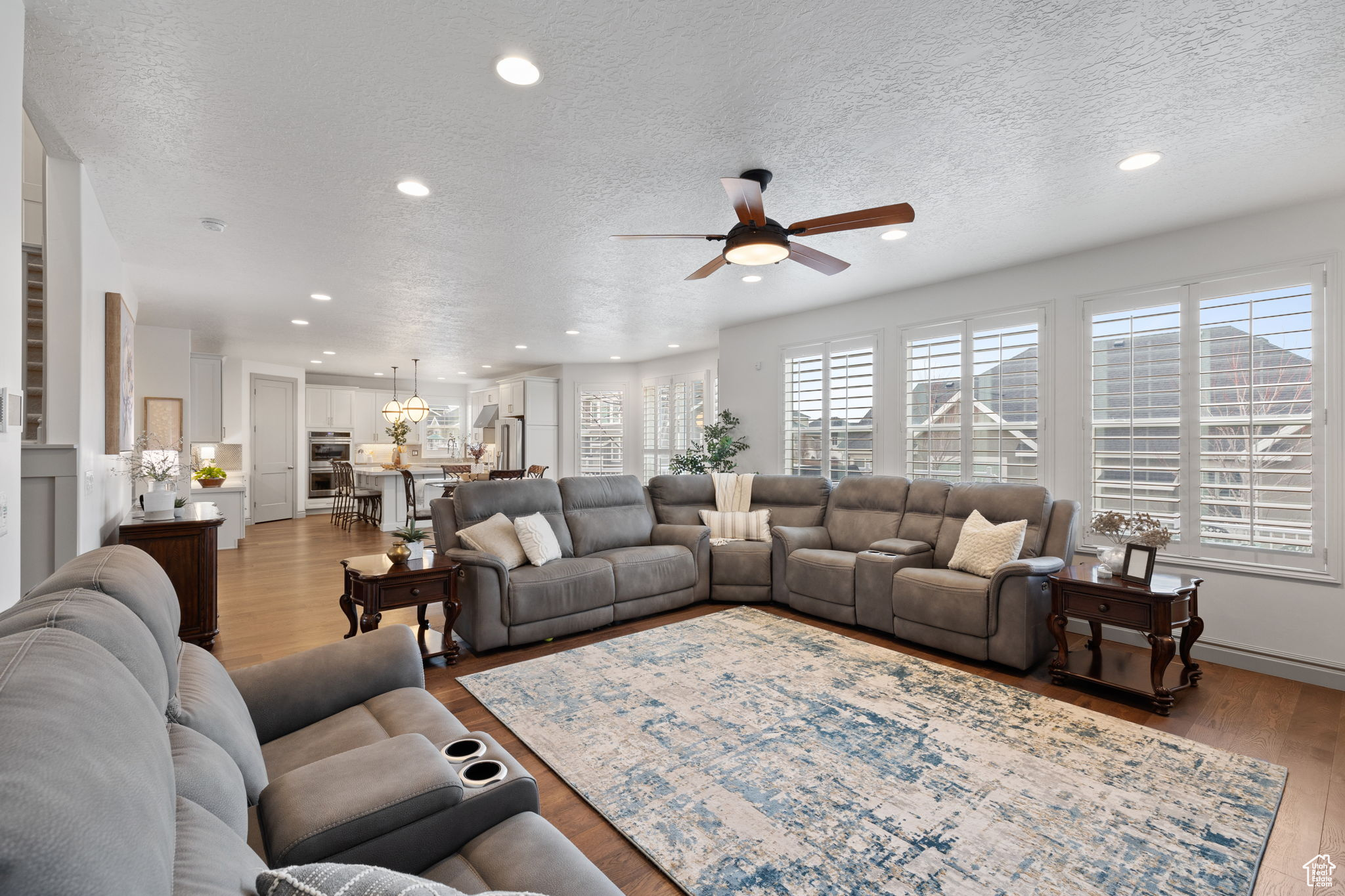 Living room featuring ceiling fan, a textured ceiling, and light hardwood / wood-style flooring