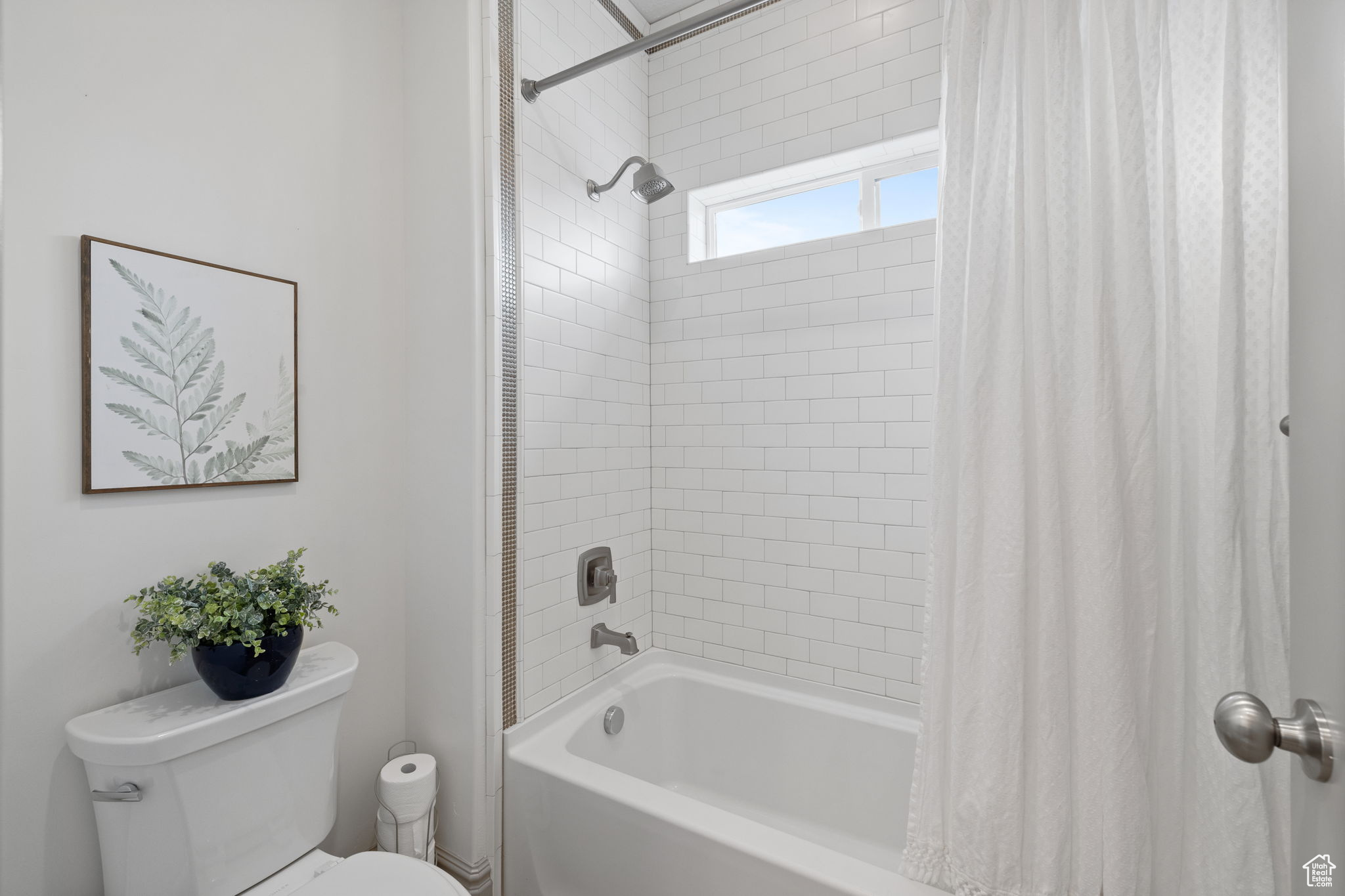 Bathroom with toilet and shower / bathtub combination with curtain