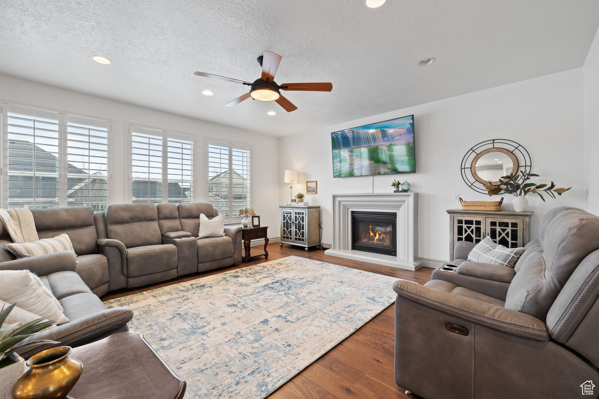 Living room featuring a textured ceiling, hardwood / wood-style flooring, and ceiling fan