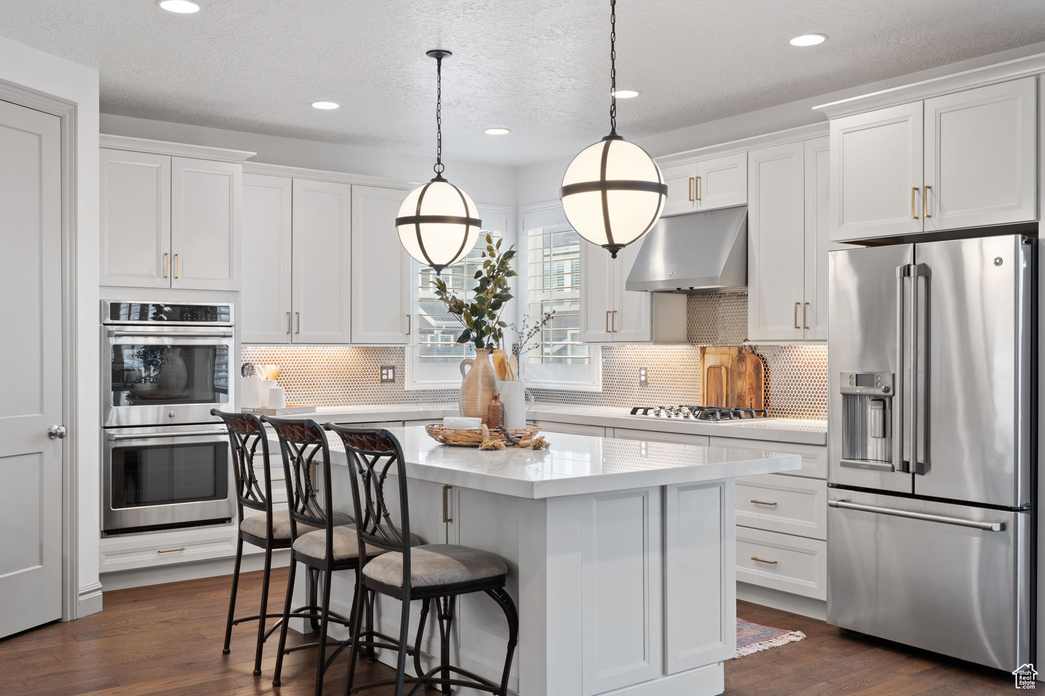 Kitchen featuring stainless steel appliances, extractor fan, white cabinetry, and a kitchen island