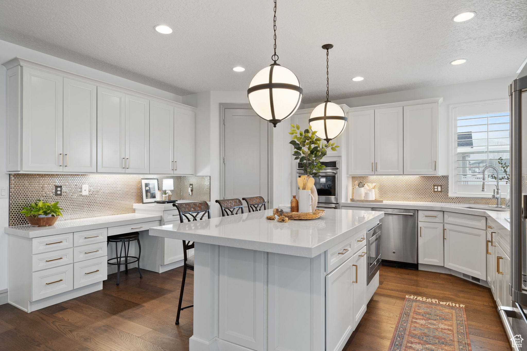 Kitchen with dishwasher, a center island, white cabinets, decorative light fixtures, and a breakfast bar area