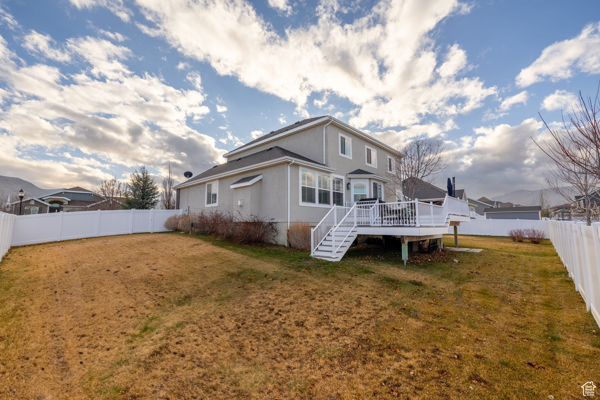 Back of property featuring a lawn and a wooden deck