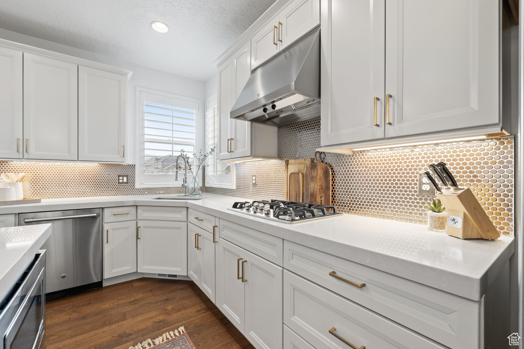 Kitchen featuring stainless steel appliances, white cabinetry, tasteful backsplash, and sink