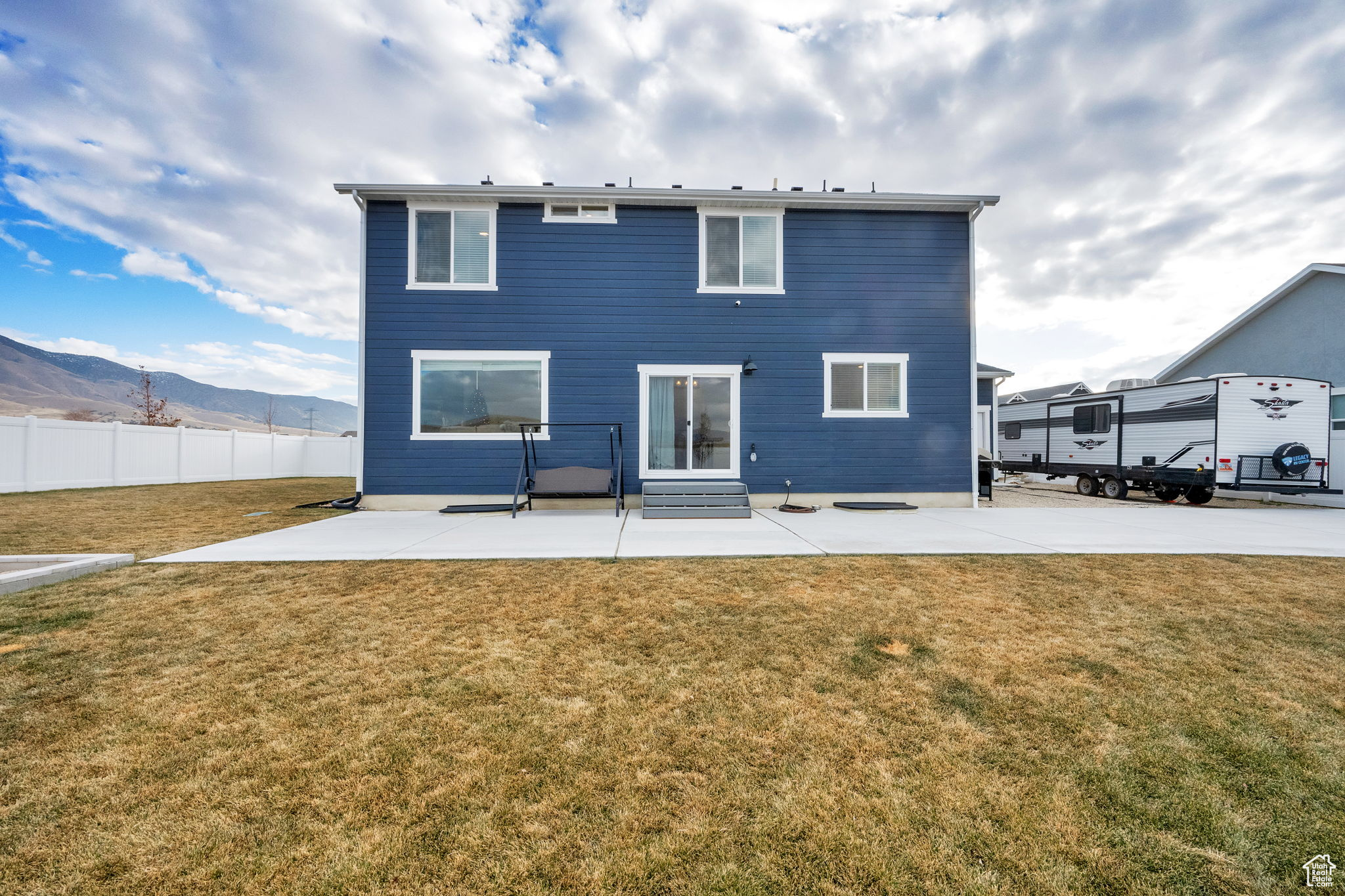 Rear view of property with a mountain view, a patio area, and a yard