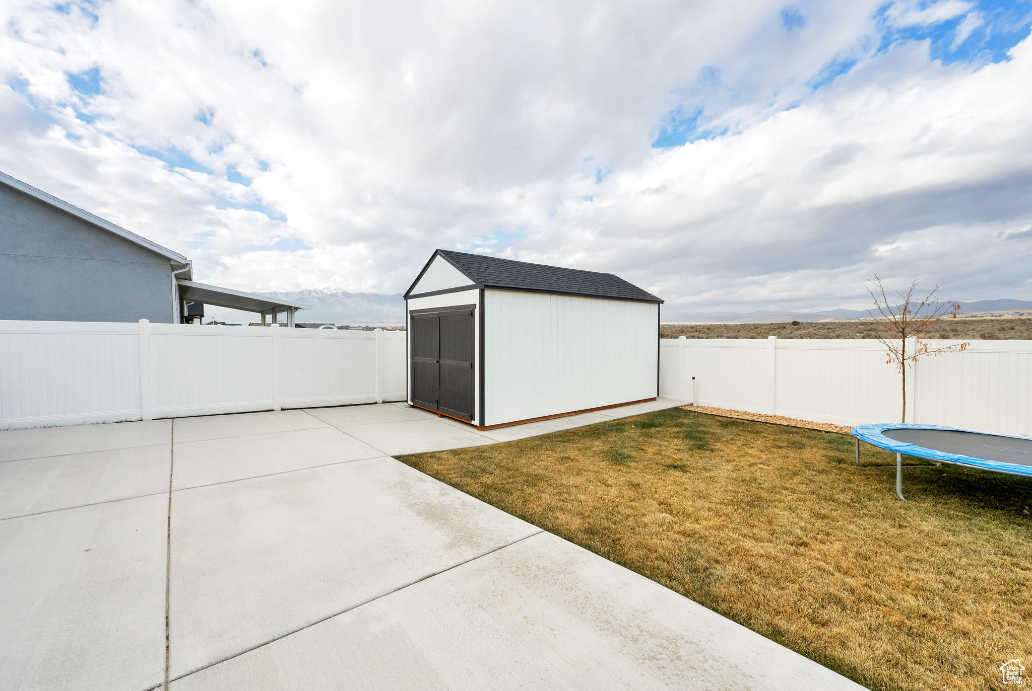 View of yard featuring a storage unit, a patio area, and a trampoline