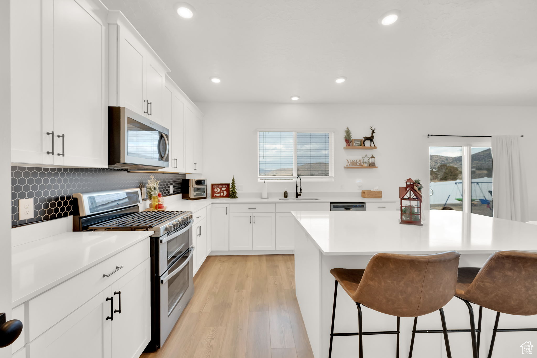 Kitchen featuring a wealth of natural light, white cabinetry, sink, a breakfast bar area, and appliances with stainless steel finishes