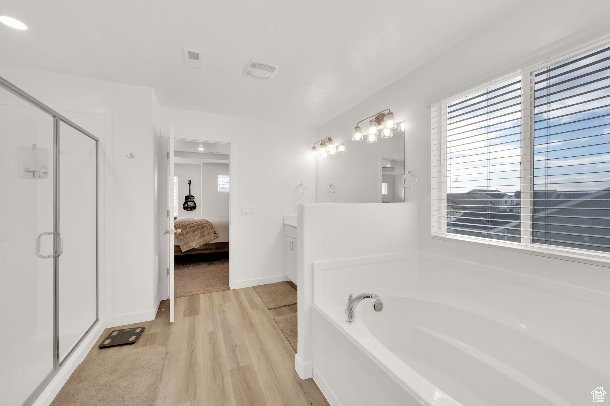 Bathroom featuring separate shower and tub, vanity, and wood-type flooring